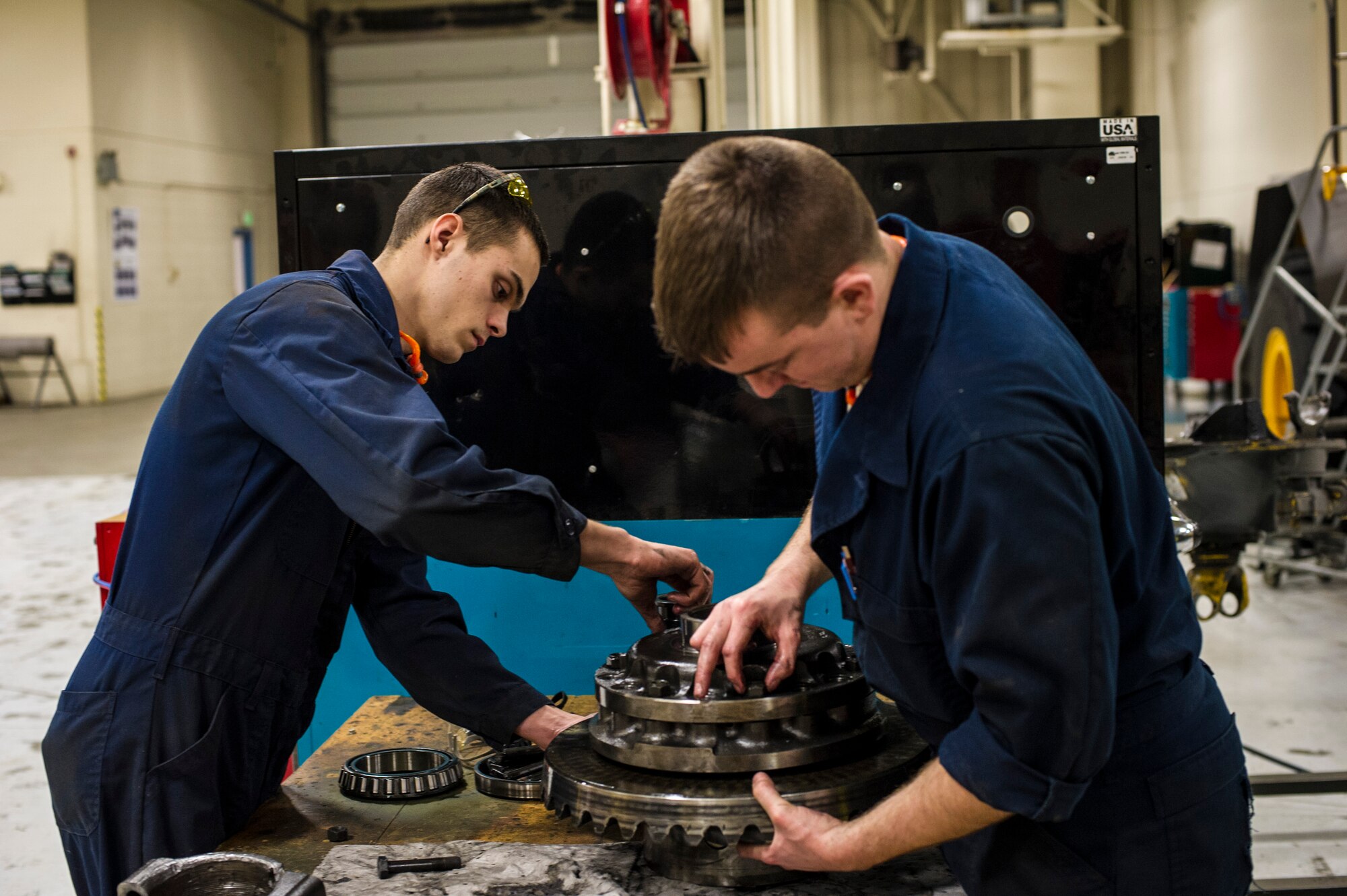 U.S. Air Force Senior Airman Anthony Tavares and Airman 1st Class Mitch Whitman, 354th Logistics Readiness Squadron vehicle maintenance flight, disassemble a differential from a flightline snow broom Jan. 9, 2014, Eielson Air Force Base, Alaska. Winter months can cover the base with snow and ice, requiring snow removal operations all week long. (U.S. Air Force photo by Senior Airman Joshua Turner/Released)