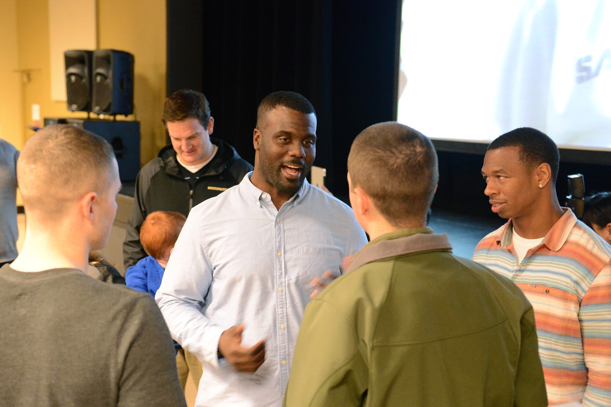 Former National Football League tight end, George Wrighster, left, and former Canadian Football League wide receiver, Samie Parker, speak with Airman 1st Class Tony Toy, 8th Airlift Squadron loadmaster, and Airman 1st Class William Buckles, 7th Airlift Squadron loadmaster, Jan. 12, 2014 at Joint Base Lewis-McChord Wash. The players joined service members and their families to watch football and socialize during the Defense Centers of Excellence Game Day Event held at JBLM, an event aimed at raising awareness among service members about the importance of reaching out for help in times of physiological distress. (U.S. Air Force photo/Airman 1st Class Jacob Jimenez)   