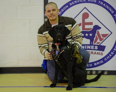 Retired Marine Cpl. Christopher Owens kneels beside his new service dog, Samaria, Jan. 9, 2014, during a ceremony at the Naval Consolidated Brig Charleston at Joint Base Charleston – Weapons Station. Samaria trained for more than a year at the NCBC as part of the Carolina Canines for Service program, a non-profit health and human services organization that trains service dogs for veterans with disabilities. (U.S. Air Force photo/Airman 1st Class Clayton Cupit)