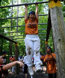 Denica Obis, a U.S. Air Force Junior Reserve Officers' Training Corps cadet, hangs onto the monkey bars as teammates cheer her on during the obstacle course challenge at Fort Eustis, Va., June 26, 2013. Fort Eustis offers two different obstacle courses for use by Service members and civilians with permission from Range Control. (U.S. Air Force photo by Staff Sgt. Dana Hill/Released)