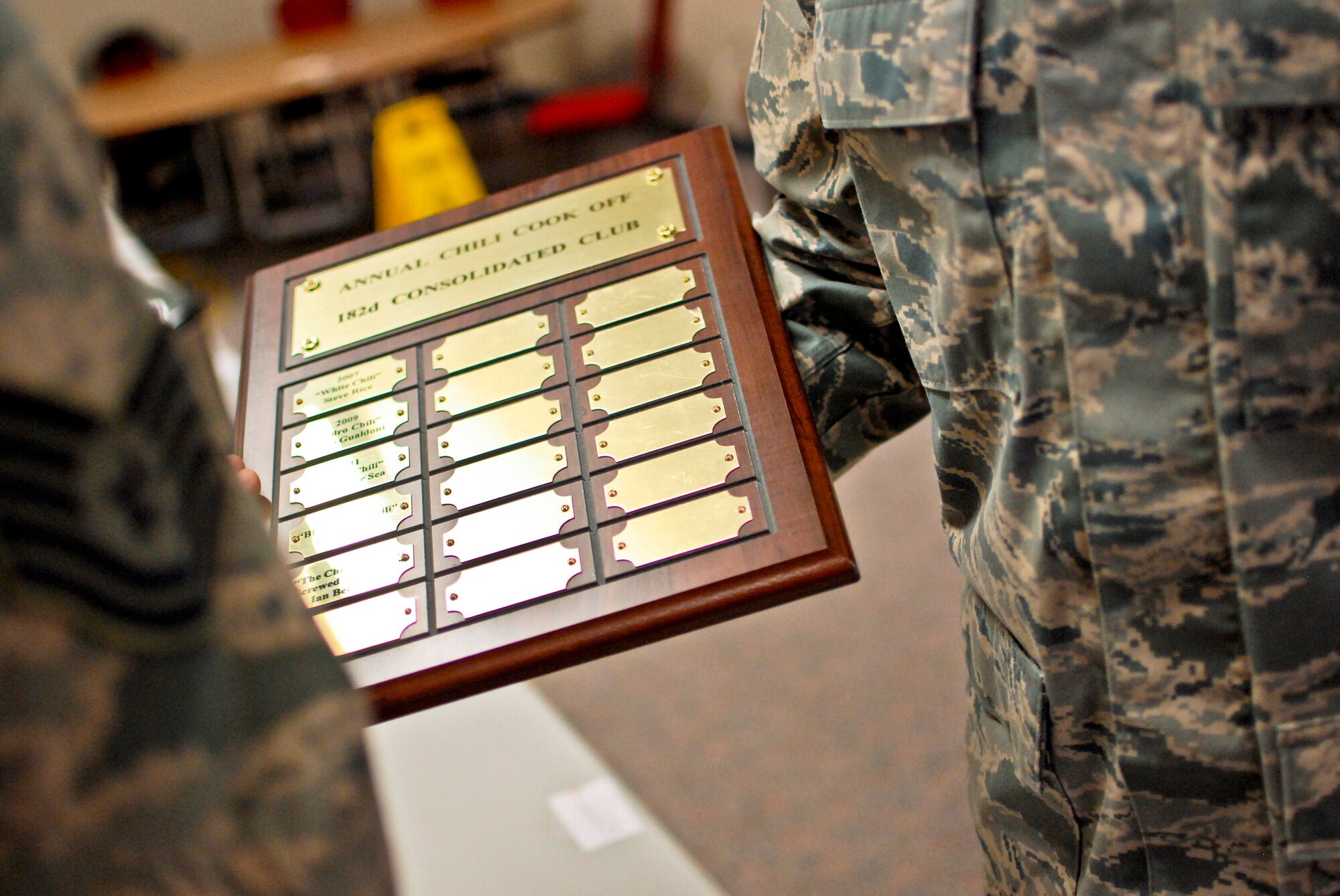 U.S. Air Force Tech. Sgt. Alex R. Sea, vehicle equipment maintenance specialist with the 182nd Logistics Readiness Squadron, right, displays the plaque of winners after the sixth-annual chili cook off at the 182nd Airlift Wing, Peoria, Ill., Jan. 8, 2014. The competition placed 13 contestants and their homemade chili recipes against each other to compete for best look and smell, best consistency, and best taste. Sea won in both the best consistency and most overall points categories for his Jabbo Chili recipe. He was awarded a five-year membership to the wing’s consolidated club and had his name added to the winners’ plaque. The event brought out approximately 120 unit members to sample the various white and traditional red entries, and raised $490 in support of operating the wing’s consolidated club. Sea enjoys the yearly event because he gets to have good chili with good people, he said. “It’s a good way to get out and mingle and talk to the people you don’t usually see on a day-to-day basis.” (U.S. Air National Guard photo by Staff Sgt. Lealan Buehrer/Released)