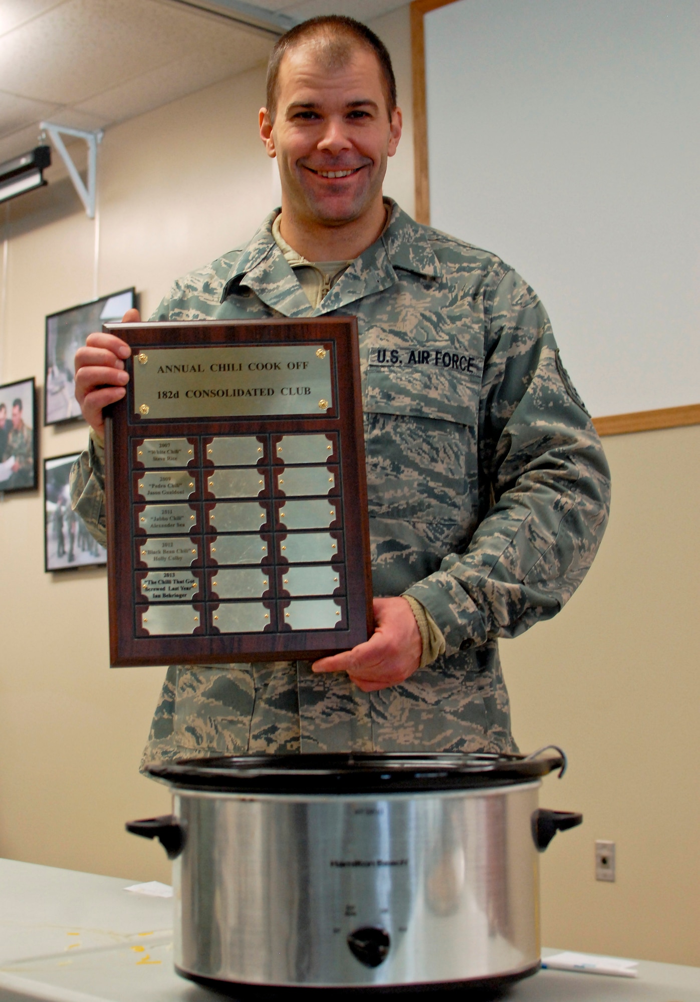 U.S. Air Force Tech. Sgt. Alex R. Sea, vehicle equipment maintenance specialist with the 182nd Logistics Readiness Squadron, displays the plaque of winners after the sixth-annual chili cook off at the 182nd Airlift Wing, Peoria, Ill., Jan. 8, 2014. The competition placed 13 contestants and their homemade chili recipes against each other to compete for best look and smell, best consistency, and best taste. Sea won in both the best consistency and most overall points categories for his Jabbo Chili recipe. He was awarded a five-year membership to the wing’s consolidated club and had his name added to the winners’ plaque. The event brought out approximately 120 unit members to sample the various white and traditional red entries, and raised $490 in support of operating the wing’s consolidated club. Sea enjoys the yearly event because he gets to have good chili with good people, he said. “It’s a good way to get out and mingle and talk to the people you don’t usually see on a day-to-day basis.” (U.S. Air National Guard photo by Staff Sgt. Lealan Buehrer/Released. Image was cropped to emphasize subject.