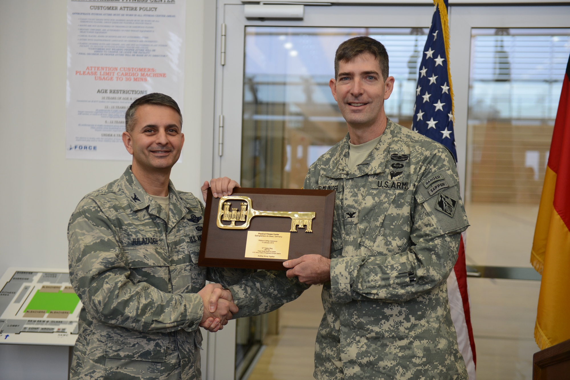SPANGDAHLEM AIR BASE, Germany – U.S. Air Force Col. David Julazadeh, 52nd Fighter Wing commander, left, receives the ceremonial key to the new fitness center from U.S. Army Col. Pete Helmlinger, commander of U.S. Army Corps of Engineers Europe district, during a ribbon cutting ceremony Jan. 13, 2014. Construction of the new $23.5 million, 69,843 square foot facility began in July 2011. (U.S. Air Force photo by Senior Airman Gustavo Castillo/Released)