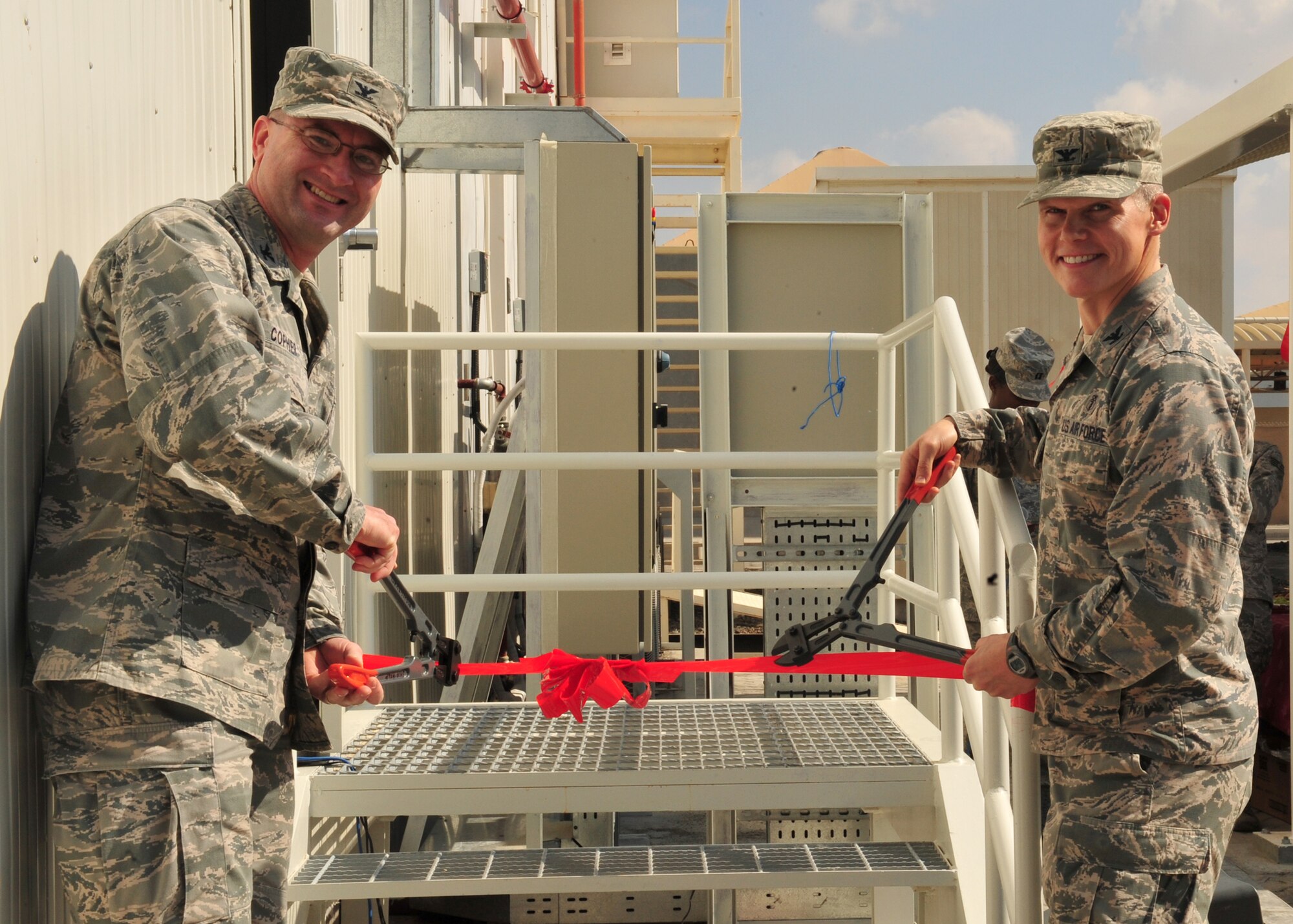 Col. James Copher, 380th Air Expeditionary Wing vice commander, and Col. Andrew Meadows, 380th Expeditionary Medical Group commander, cut the ceremonial ribbon during the celebration of the medical clinic expansion at an undisclosed location in Southwest Asia, Dec. 29, 2013. The construction of the facility began in February 2013. (U.S. Air Force photo by Tech. Sgt. Colleen Urban/Released) 