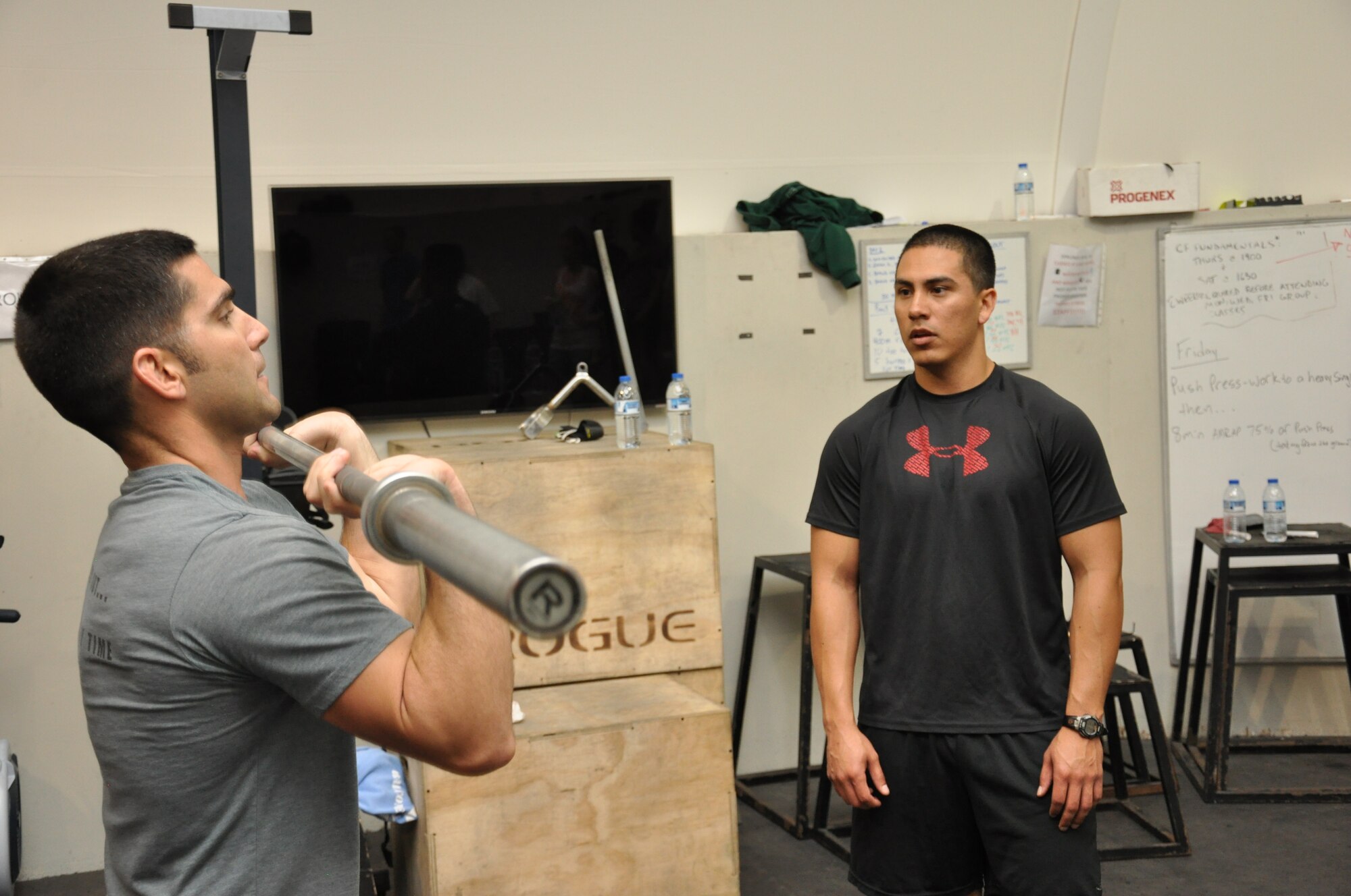 Air Force Capt. Sam Murray, 380th Expeditionary Security Forces Squadron operations officer in charge, demonstrates the proper way to hold the bar in the front rack position to Air Force Senior Airman Emmanuel Arroyo, 380th Expeditionary Logisics Readiness Squadron supply specialist, during a class at the tactical fitness facility at an undisclosed location in Southwest Asia, Jan. 3, 2014. (U.S. Air Force photo by Maj. Khalid Cannon/Released)