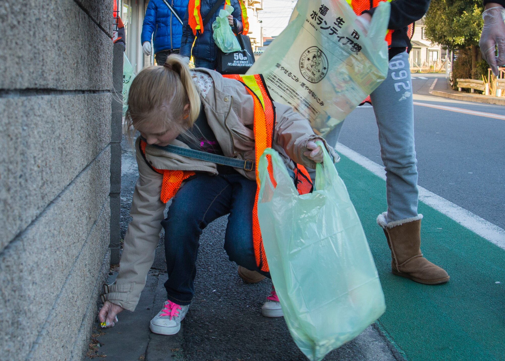 Caitlin Beard, a volunteer worker from Yokota Youth Center, picks up trash during a volunteer cleanup honoring Martin Luther King Jr. Day at Fussa City, Japan, Jan. 11, 2014.  More than 20 youths and teens volunteered to clean the streets of Fussa City.  (U.S. Air Force photo by Airman 1st Class Soo C. Kim / Released)