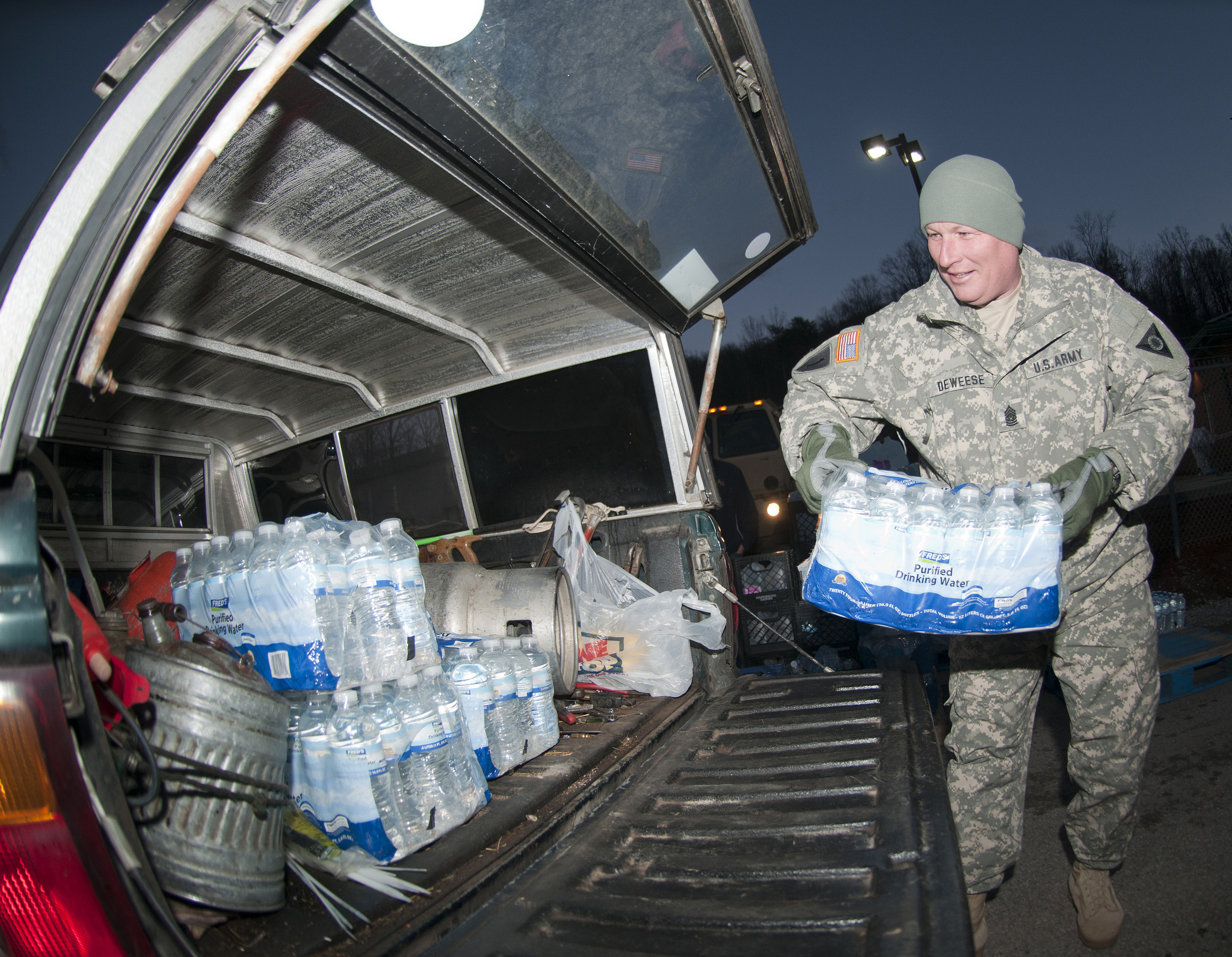 Army Command Sgt. Maj. Steve Deweese loads water into a vehicle at the