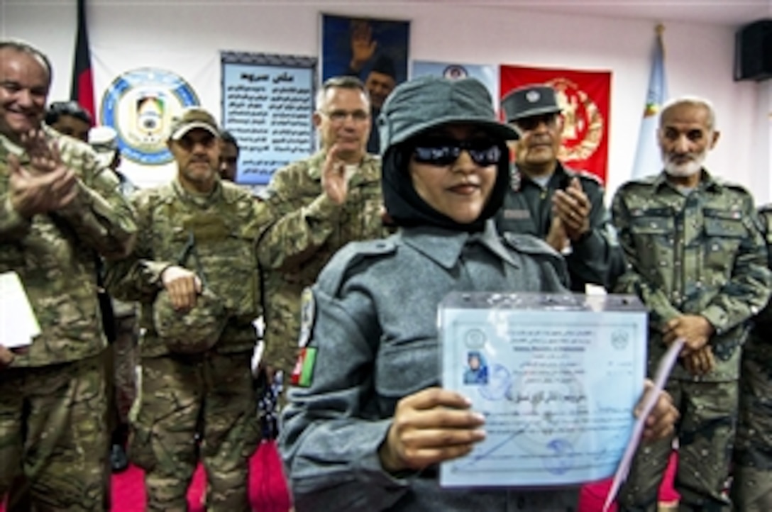 One of the first all-female Afghan graduates from the national basic patrolman's course holds a graduation certificate at the Joint Regional Afghan National Police Center in Afghanistan's Kandahar province, Jan. 9, 2014, as U.S. and Afghan leaders applaud. 