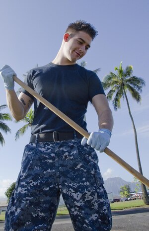Seaman Jake Barcus, aviation ordnanceman, Base Ordnance, rakes grass clippings across the street from Pless Hall during Malama Ka Aina, Dec. 3, 2013. During Malama Ka Aina, a biannual event at Marine Corps Base Hawaii, all units aboard the base participate in major cleaning efforts, from retrieving garbage in the waterways to clearing weeds and sweeping the sidewalks. (U.S. Marine Corps photo by Kristen Wong)