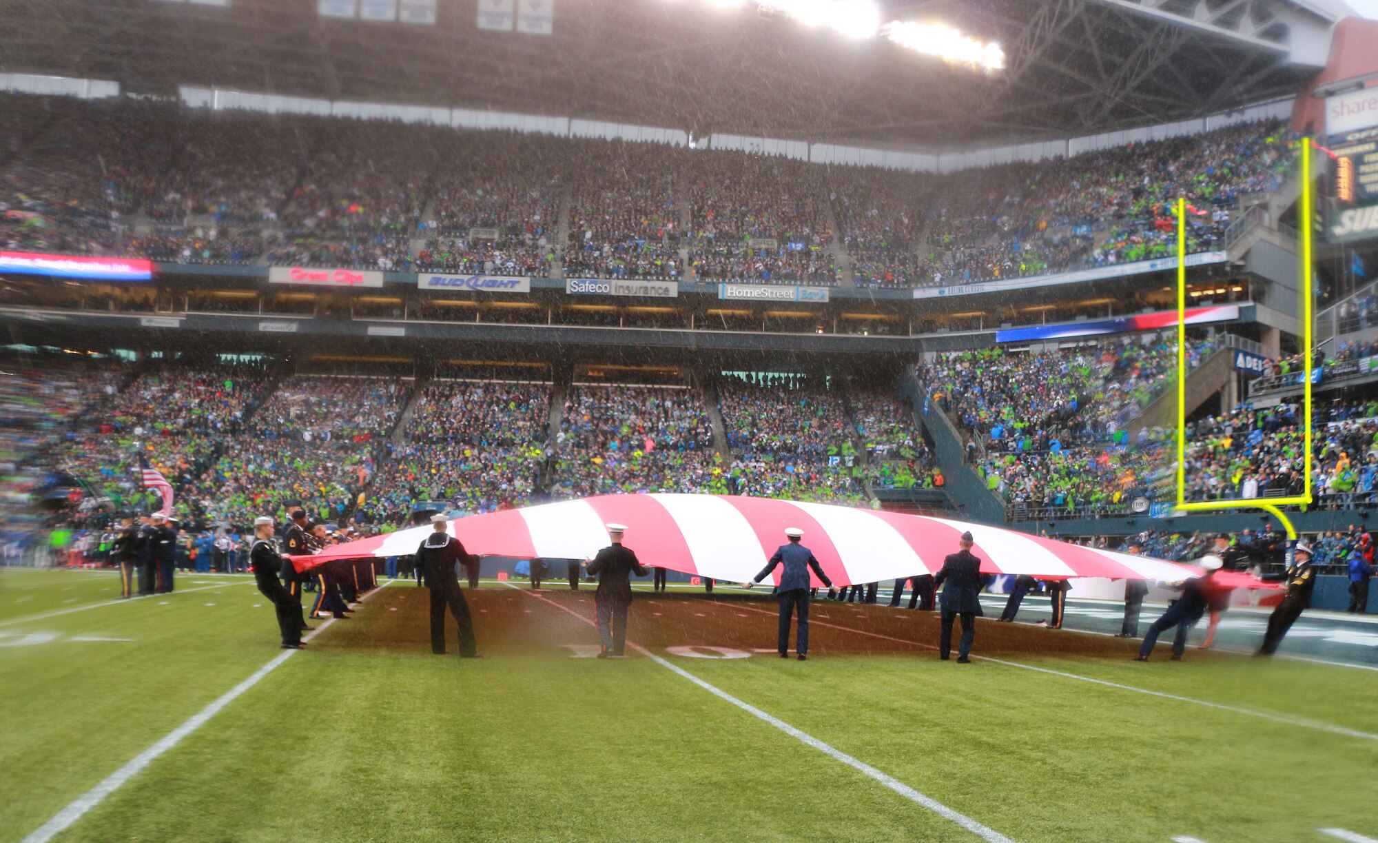Despite the less than ideal weather conditions at the Seattle Seahawks game, Jan. 11 at Century Link Field in Seattle, Wash., Team McChord Airmen along with 40 members from the other service branches, stood together to present the U.S. flag during the pregame ceremonies.  The Seahawks also embraced the elements without faltering, defeating the New Orleans Saints 23-15 and winning the divisional round. (U.S. Air Force photo by Senior Airman Madelyn McCullough)