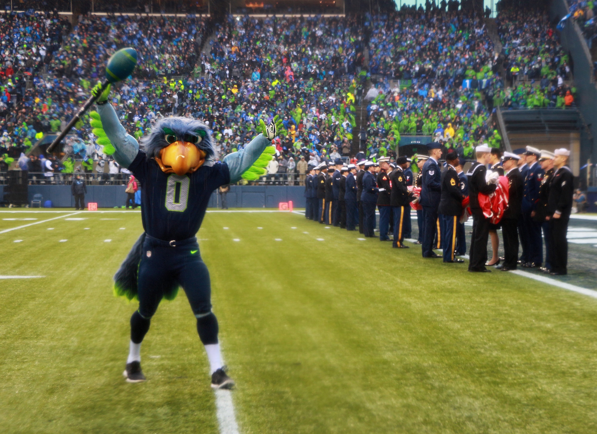 Blitz, the Seattle Seahawks mascot, gets the crowd roaring while Reservists from the 446th Airlift Wing carry the U.S. flag as part of the pregame ceremonies, Jan. 11, 2013 at Century Link Field in Seattle, Wash. Members from each branch of service stood together and presented the flag at the 2014 NFC Divisional game against the New Orleans Saints. (U.S. Air Force photo by Senior Airman Madelyn McCullough)