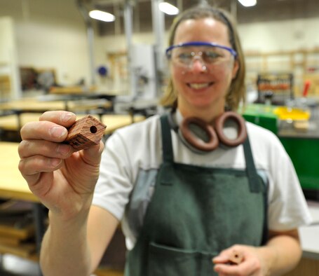 Patty Morales, 92nd Force Support Squadron woodcraft staff, shows the progress made by using the drill press in the wood craft center at Fairchild Air Force Base, Wash., Jan. 13, 2013. Morales is in the process of making a wooden pen for the course held at the shop. (U.S. Air Force photo by Airman 1st Class Ryan Zeski/Released)
