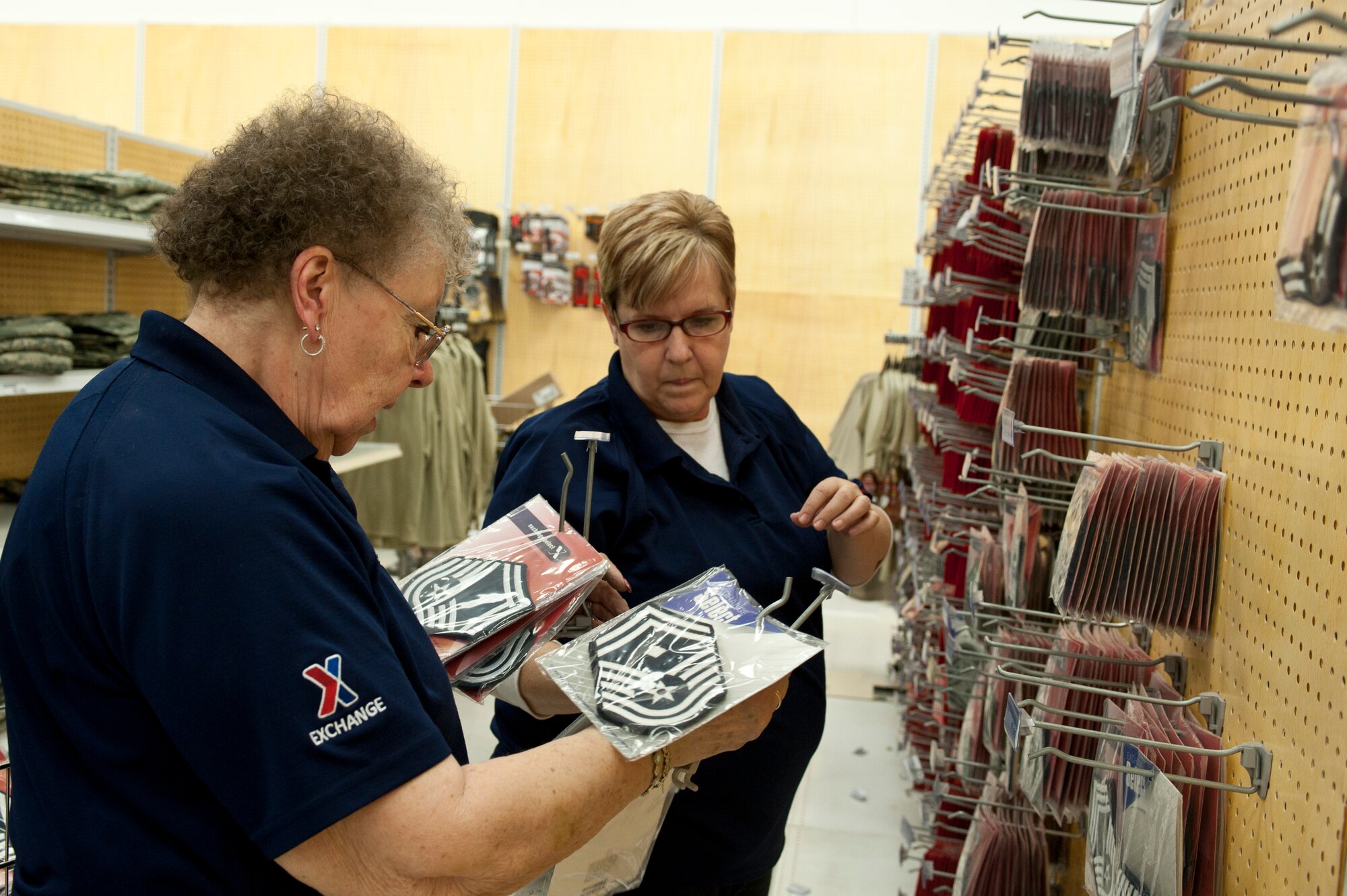 Judy Olisky (left), an Exchange senior sales associate, and Cheryl Miller (right), an Exchange service business associate, sort through enlisted military ranks in the Exchange during the move of clothing sales Jan. 10, 2014, at Nellis Air Force Base, Nev. Military clothing sales will undergo an eight-week renovation project that will cost $160,000. (U.S. Air Force photo by Senior Airman Matthew Lancaster)