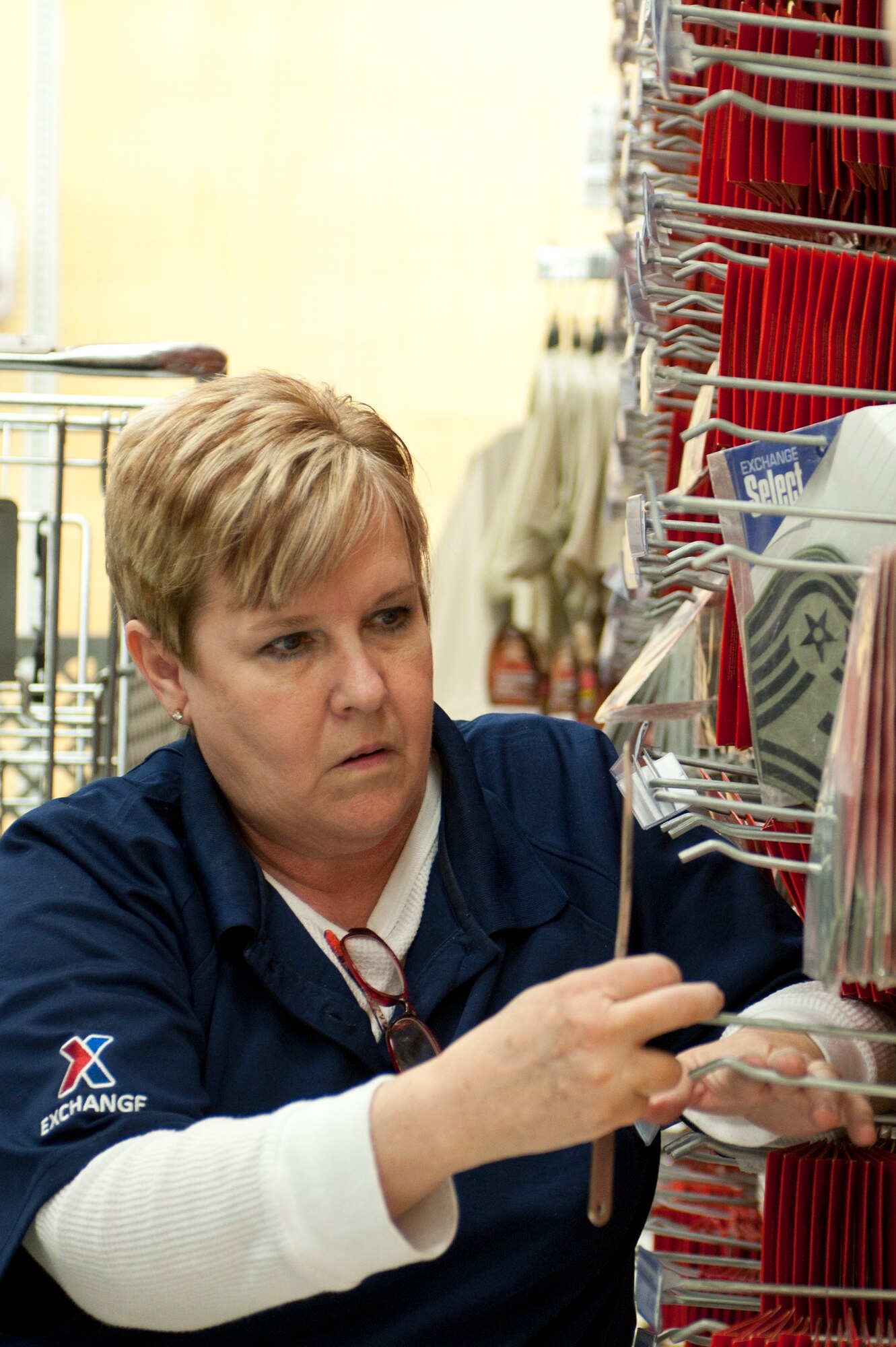 Cheryl Miller, an Exchange service business associate, stocks military ranks in the Exchange during the move of clothing sales Jan. 10, 2014, at Nellis Air Force Base, Nev. The Exchange employees moved all the items out of clothing sales in preparation for a renovation project that began Monday Jan. 13. (U.S. Air Force photo by Senior Airman Matthew Lancaster)