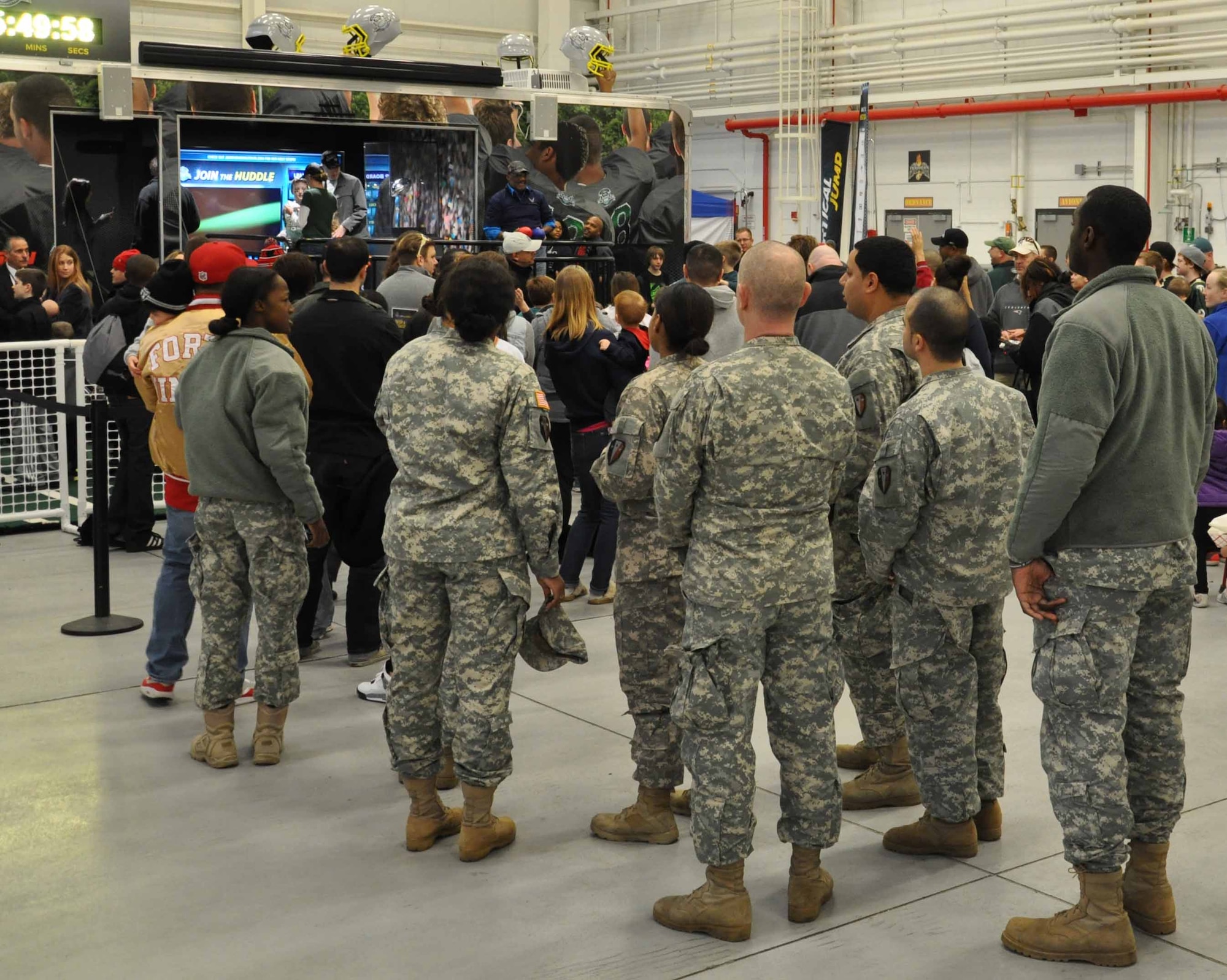 Service members and their families wait in line to experience the NFL’s “Join the Huddle” tour inside Marine Heavy Helicopter Squadron (HMH) 772 Hangar Jan. 12, 2014, at Joint Base McGuire-Dix-Lakehurst, N.J. The rolling Super Bowl exhibit, known as the Huddle Shuttle, housed Super Bowl memorabilia, including the Vince Lombardi Trophy. (U.S. Air Force photo by 2nd Lt. Carrie Volpe/Released)