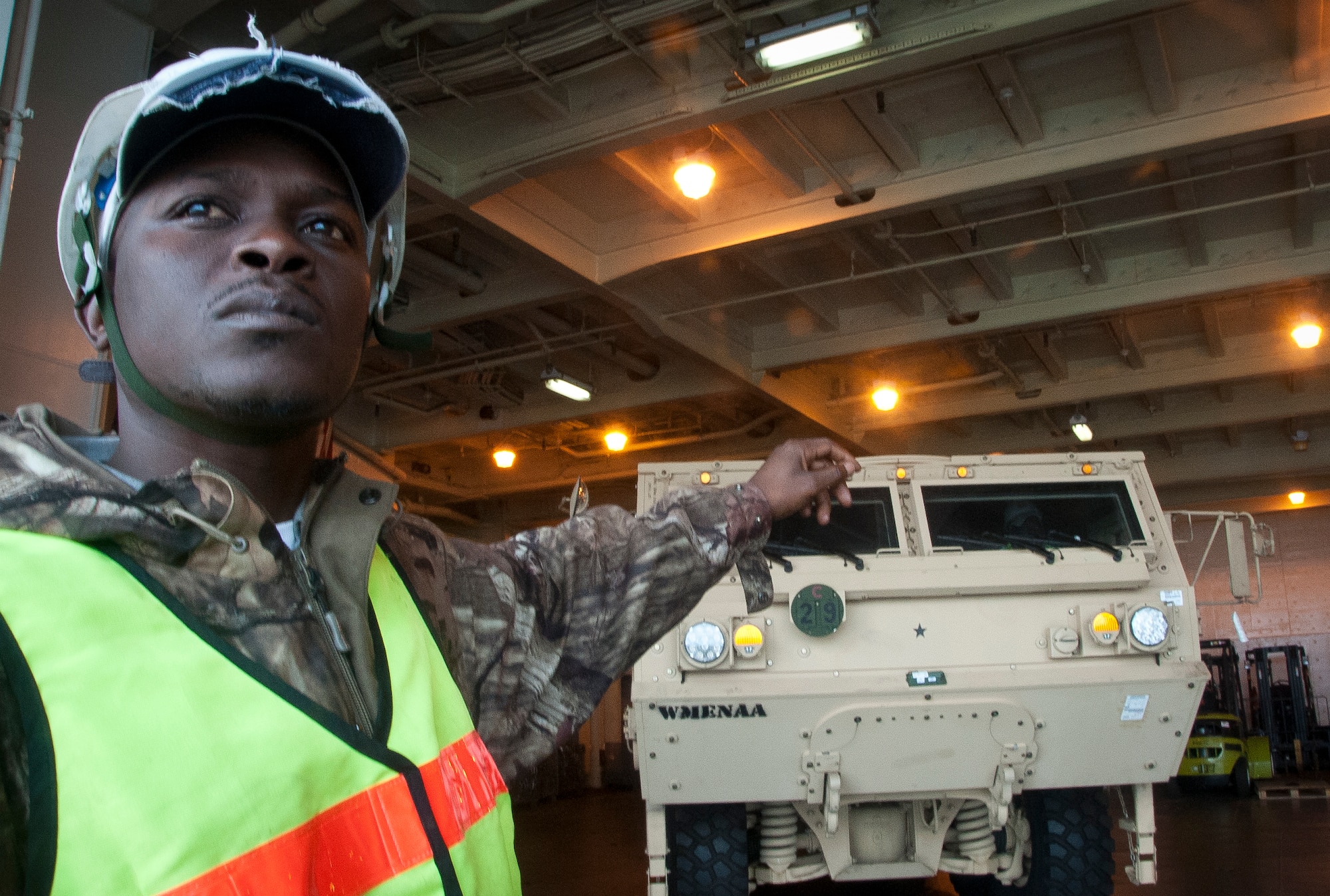 Darriel Porcher, International Longshoremen's Association flagman, directs a truck as it if off-loaded from the USNS Pomeroy (T-AKR-316),  Jan. 10, 2014. The Pomeroy contains sustainment brigade sets consisting of supplies ranging from fuel tankers, fork-lifts, wreckers, cargo containers, rough terrain container handlers and ammunition. This year, the 841st Transportation Battalion is slated to receive four Army Prepositioned Stock Vessels. (U.S. Air Force photo/Staff Sgt. William O’Brien)