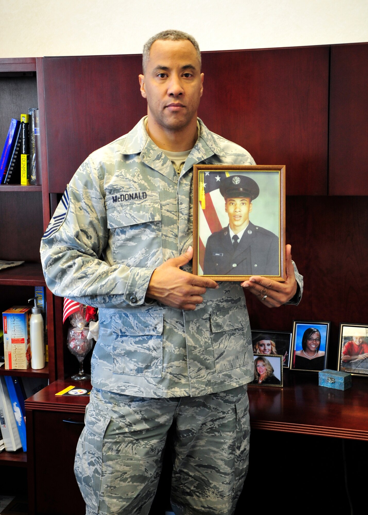 Chief Master Sgt. James McDonald, 436th Aerial Port Squadron superintendent, poses with a picture of himself from his graduation from basic training Dec. 19, 2013, at Dover Air Force Base, Del. McDonald spent 30 years as an active duty enlisted member in the Air Force before retiring. (U.S. Air Force photo/Airman 1st Class William Johnson)