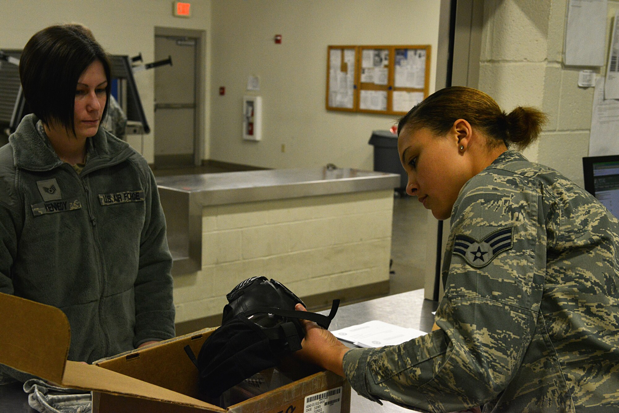 U.S. Air Force Staff Sgt. Natalia Kennedy (left), 20th Component Maintenance Squadron propulsion materials support technician, watches as Senior Airman Jade Graham (right), 20th Logistics Readiness Squadron individual protective equipment journeyman, checks the serial number on a gas mask at the Chandler Deployment Processing Center, Shaw Air Force Base, S.C., Jan. 8, 2014.  Kennedy watched Graham check all of the serial numbers on each of the nine components of the gas mask before it was issued to her in preparation for an operation readiness exercise. (U.S. Air Force photo by Airman 1st Class Jensen Stidham/Released)