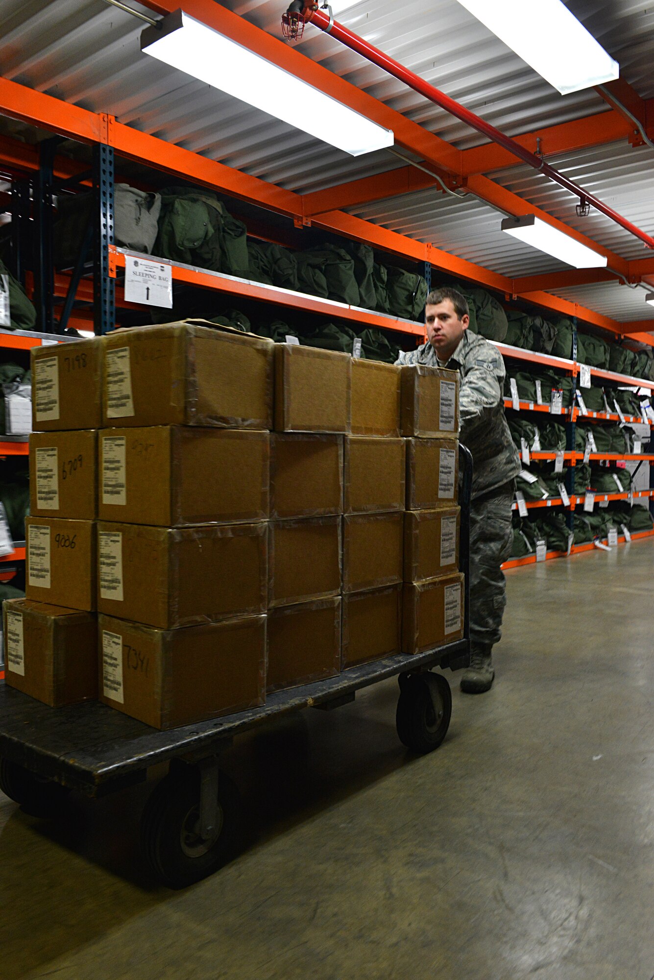 U.S. Air Force Senior Airman Aaron Burchette, 20th Logistics Readiness Squadron individual protective equipment journeyman, pushes a cart of gas mask boxes at the Chandler Deployment Processing Center, Shaw Air Force Base, S.C., Jan. 9, 2014. Burchette was moving the boxes closer to the pick-up windows where Airmen had lined up to be issued a gas mask for an operational readiness exercise. (U.S. Air Force photo by Airman 1st Class Jensen Stidham/Released)