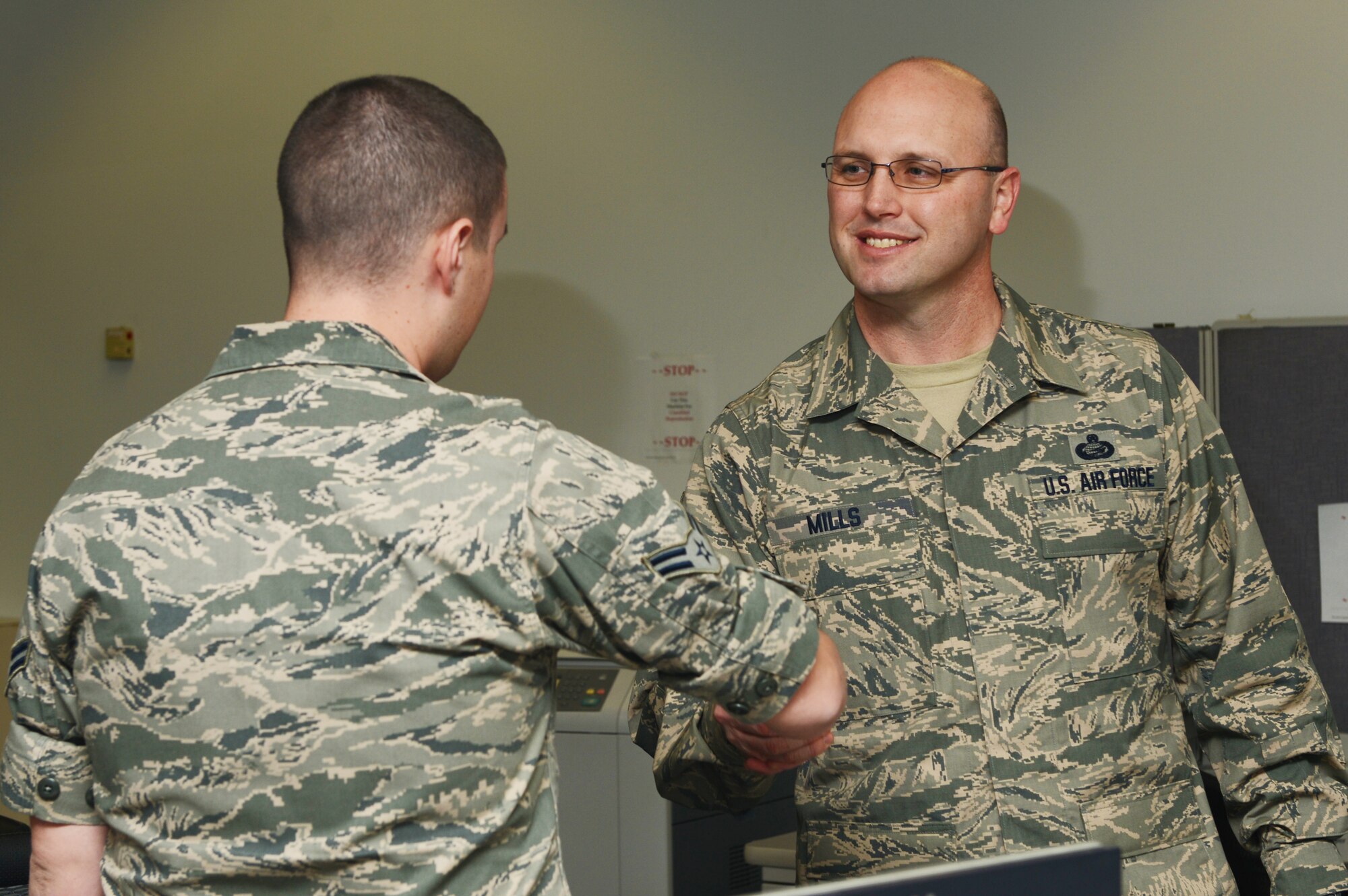 U.S. Air Force Chief Master Sgt. Charles Mills (Right), 20th Fighter Wing command chief, shakes the hand of U.S. Air Force Airman 1st Class Chad Robertson (left), 20th Comptroller Squadron financial services technician, in the finance office at Shaw Air Force Base, S.C., Jan. 13, 2014. Mills went around to different offices meeting and talking with the Airmen in his wing. (U.S. Air Force photo by Airman 1st Class Diana M. Cossaboom/Released)