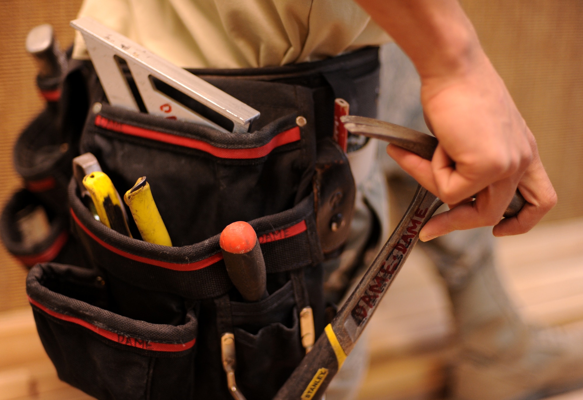 U.S. Air Force Tech. Sgt Giles Dame, 18th Civil Engineer Squadron structural craftsmen, grabs his hammer from his tool belt on Kadena Air Base, Japan, Jan. 8, 2014. The 18th CES structure shop manages, constructs, repairs, and modifies structural systems to include wooden, masonry, metal, and concrete buildings. (U.S. Air Force photo by Airman 1st Class Keith James)