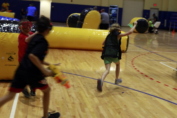 Children sprint across the gym during a Morale, Welfare and Recreation event at Naval Support Activity Bahrain Nov. 21, 2013. Marines from Command Element, Marine Forces Central Command (Forward) and Fleet Antiterrorism Security Team, Central Command battled against Department of Defense employees’ children for the event where they had to make it across the gym, grab the flag, and return it to their “base,” before the other team.