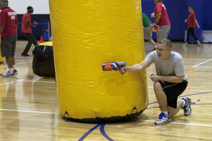 Cpl. Paul T. Brinson, an intelligence analyst with Command Element, Marine Forces Central Command (Forward), hides behind an inflatable obstacle during a Morale, Welfare and Recreation event at Naval Support Activity Bahrain Nov. 21, 2013. Marines from Command Element, Marine Forces Central Command (Forward) and Fleet Antiterrorism Security Team, Central Command battled against Department of Defense employees’ children for the event where they had to make it across the gym, grab the flag, and return it to their “base,” before the other team.