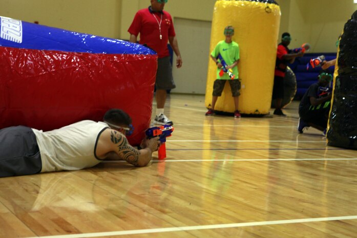Cpl. Maxwell D. Klien, a Marine with Command Element, Marine Forces Central Command (Forward), hides behind an inflatable obstacle during a Morale, Welfare and Recreation event at Naval Support Activity Bahrain Nov. 21, 2013. Marines from CE, MARFOR CENTCOM (Fwd) and Fleet Antiterrorism Security Team, Central Command battled against Department of Defense employees’ children for the event where they had to make it across the gym, grab the flag, and return it to their “base,” before the other team.