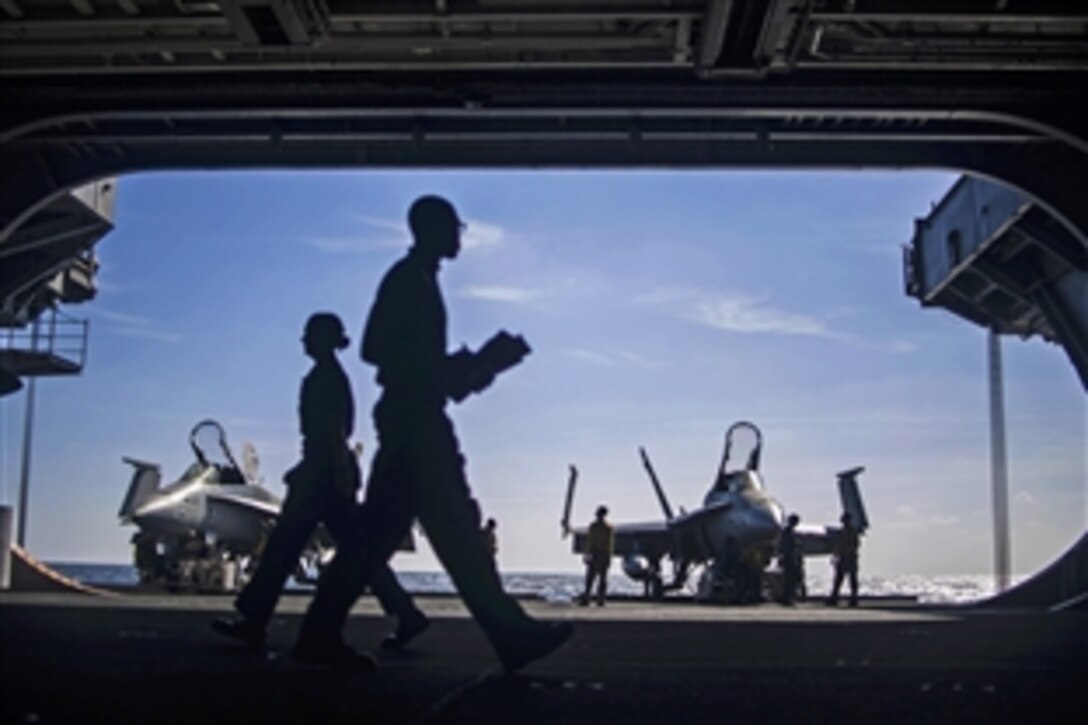 Crew members prepare F/A-18C Hornets for transport from the aircraft elevator to the hangar bay on the USS Harry S. Truman in the Gulf of Oman, Jan. 10, 2014. The Truman, flagship for the Harry S. Truman Carrier Strike Group, is deployed to the U.S. 5th Fleet area of responsibility to conduct maritime security operations and support theater security cooperation efforts.