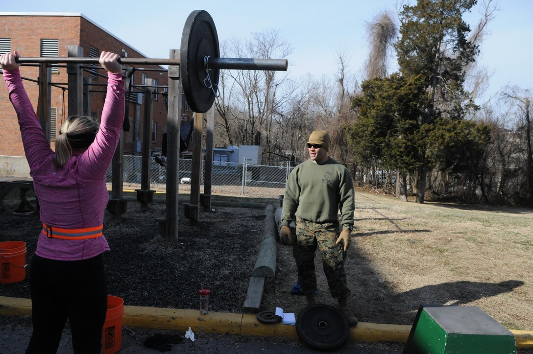 CrossFit Quantico coach Capt. Adam Tabalno advises Shanna Bonaudi, whose husband is attending the Expeditionary Warfare School, on proper push press form during the Jan. 8, 2014, workout.  
