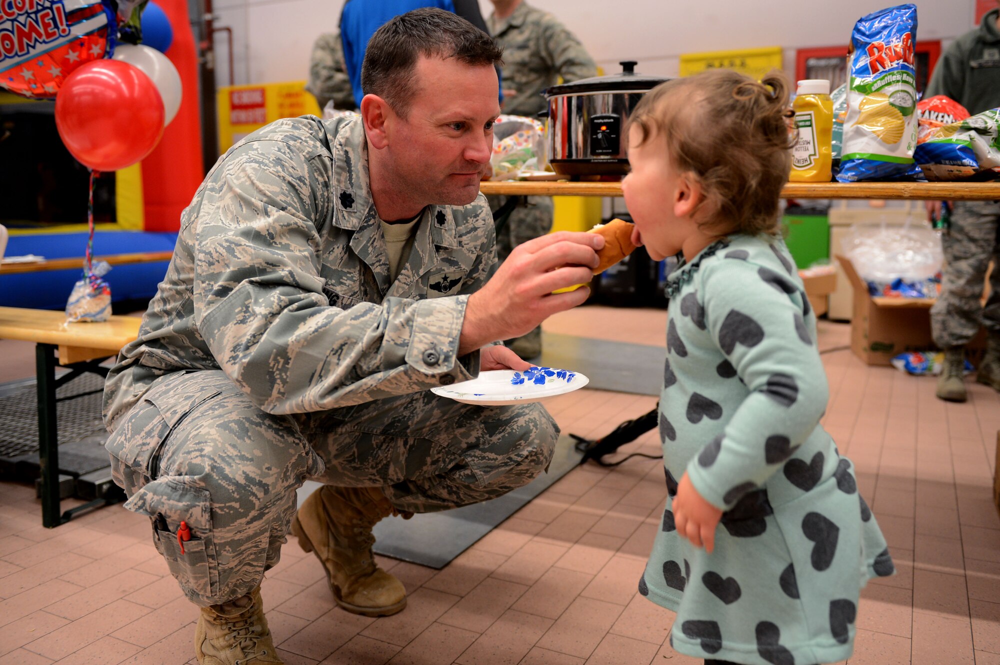 SPANGDAHLEM AIR BASE, Germany –U.S. Air Force Lt. Col. Robert Long, 606th Air Control Squadron commander, feeds a hot dog to his daughter, Adrianna, Jan. 15, 2014. Long and his squadron returned from a six-month deployment to Southwest Asia. The 606th ACS is one of the 52nd Operations Group’s three squadrons which comprise the flying component of the 52nd Fighter Wing. (U.S. Air Force photo by Airman 1st Class Kyle Gese/Released)