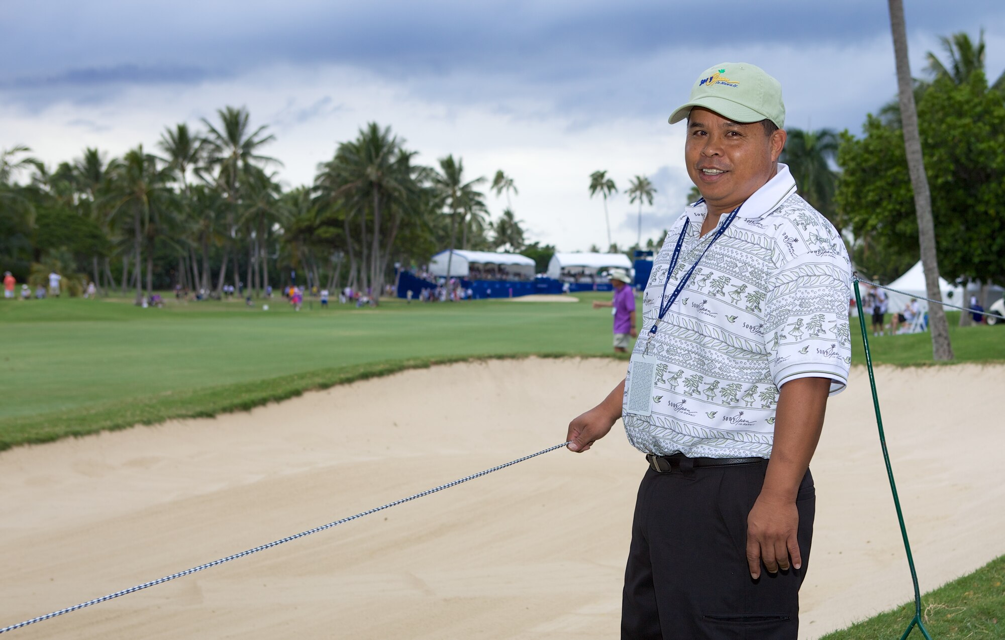 Tech. Sgt. Ed Dumlao, a water fuels systems maintenance journeyman with the 624th Civil Engineering Squadron, poses for a photo on the 18th fairway at the Sony Open PGA Tour golf tournament, Waialae Country Club, Honolulu, Hawaii, Jan. 11, 2014. Dumlao volunteered to operate a survey-grade laser on the 14th fairway, recording everything from the location of each ball, the lie, the distance it travels and the time it is struck. Dumlao was supporting the Friends of Hawaii Charities, a non-profit organization whose principal fund-raising event is the Sony Open. (Courtesy photo by Kristopher Schlund/Released)