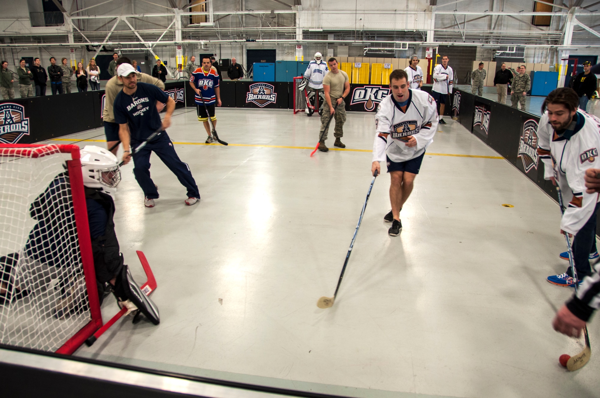 Master Sergeant Chris Shamiyeh slides to his right blocking Oklahoma City Barons’ Richard Bachman’s shot during a floor hockey game in the Maintenance Squadron hangar January 14, 2014.  Bachman was one of four Barons players to volunteer for the game here as part of a winning raffle by 507th Civil Engineering Squadron’s Senior Master Sgt. Daniel Bostwick.  Five members from the 507th and 137th Oklahoma Air National Guard Air Refueling Wings participated in the game as dozens more took time to come watch.  The four Barons hockey players along with two cheerleaders toured a KC-135R Stratotanker prior to the game.  The Oklahoma City Barons are part of the National Hockey League’s Edmonton Oilers.  (U.S. Air Force photo/Senior Airman Mark Hybers)