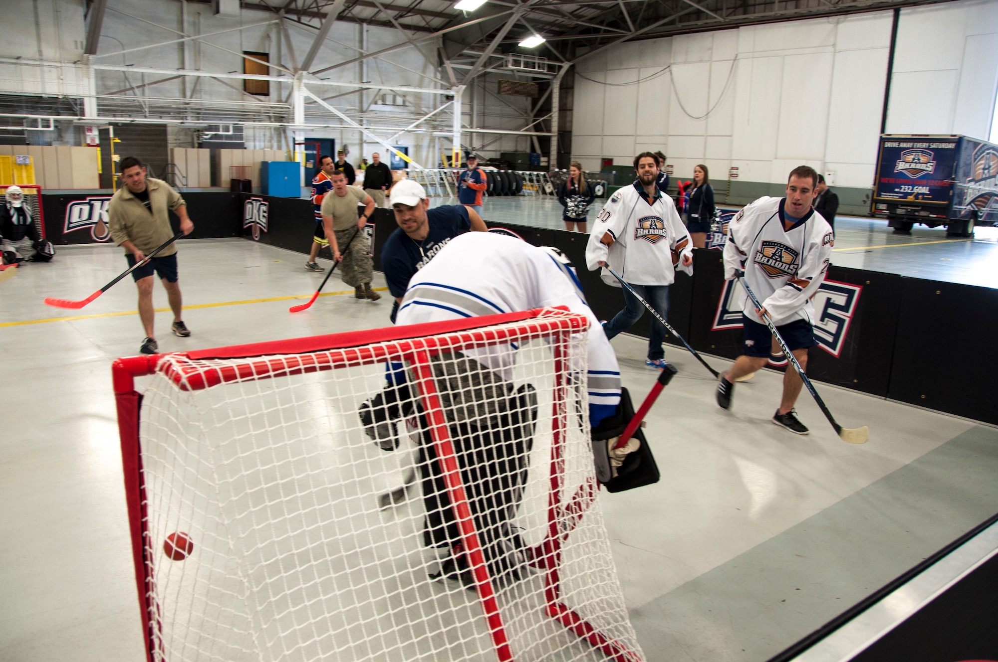 Oklahoma City Barons’ Bradley Hunt scorches 507th Operations Group Intelligence Superintendent Senior Master Sgt. Bob Gaspar on a shot from the corner of the makeshift rink during the floor hockey game here January 14, 2014.  Hunt was one of four Barons players to volunteer for the game here as part of a winning raffle by 507th Civil Engineering Squadron’s Senior Master Sgt. Daniel Bostwick.  Five members from the 507th and 137th Oklahoma Air National Guard Air Refueling Wings participated in the game as dozens more took time to come watch.  The four Barons hockey players along with two cheerleaders toured a KC-135R Stratotanker prior to the game.  The Oklahoma City Barons are part of the National Hockey League’s Edmonton Oilers.  (U.S. Air Force photo/Senior Airman Mark Hybers)