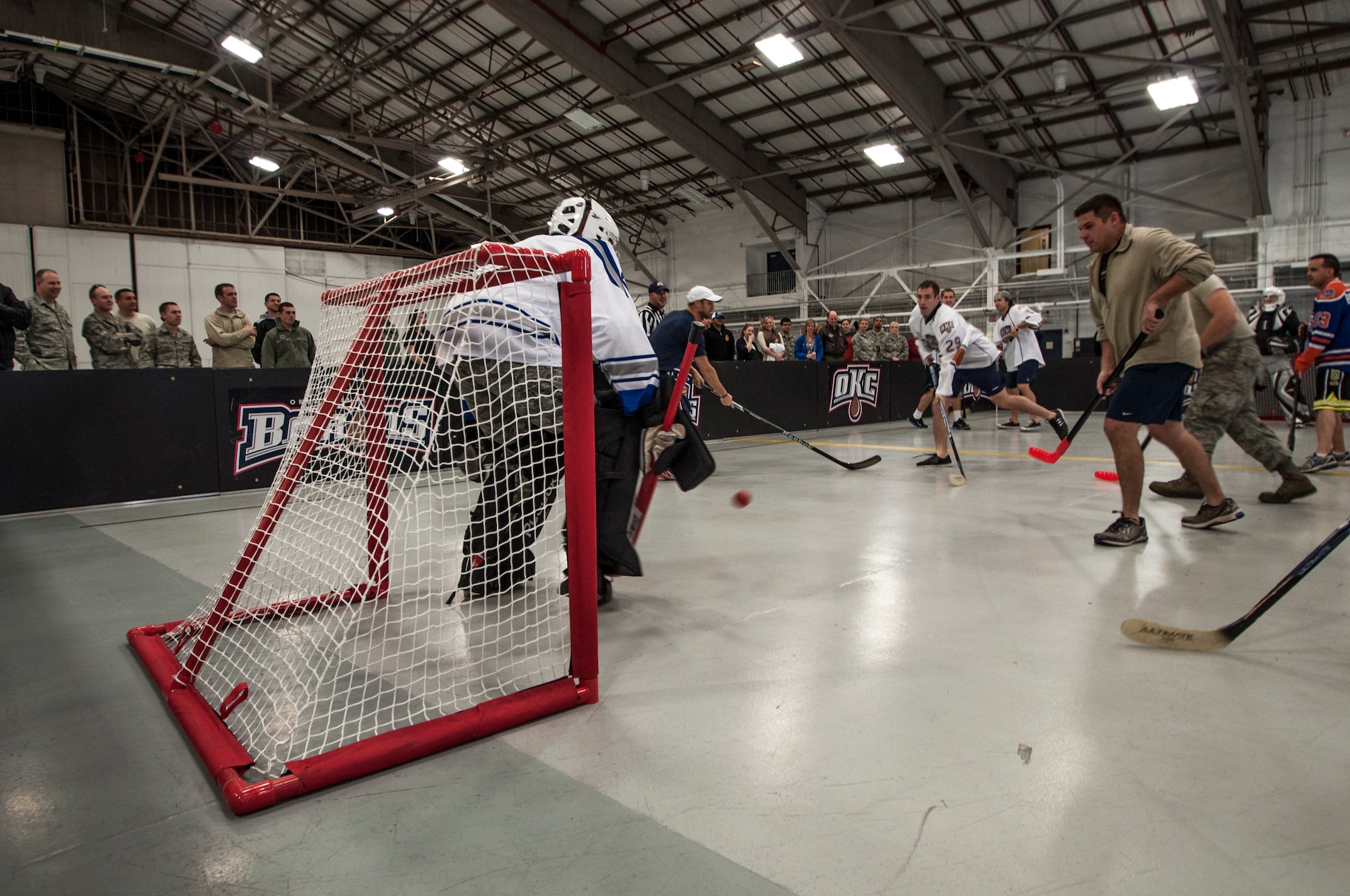 Senior Master Sergeant Bob Gaspar, 507th Operations Group superintendent of intelligence, stops a point blank shot from Oklahoma City Barons hockey player, Bradley Hunt during a floor hockey game January 14, 2014 in the Maintenance Squadron hangar.  Hunt was one of four Barons players to volunteer for the game here as part of a winning raffle by 507th Civil Engineering Squadron’s Senior Master Sgt. Daniel Bostwick.  Five members from the 507th and 137th Oklahoma Air National Guard Air Refueling Wings participated in the game as dozens more took time to come watch.  The four Barons hockey players along with two cheerleaders toured a KC-135R Stratotanker prior to the game.  The Oklahoma City Barons are part of the National Hockey League’s Edmonton Oilers.  (U.S. Air Force photo/Senior Airman Mark Hybers)