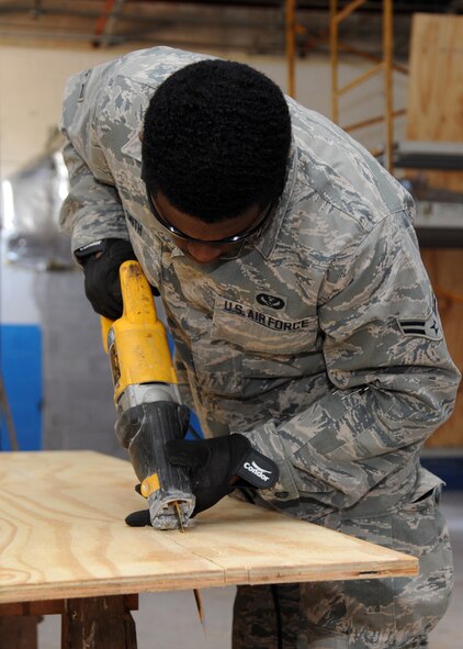 Airman 1st Class Brandyn Smith, 307th RED HORSE Civil Engineer Squadron structural engineer, uses a reciprocating saw to cut plywood at the Airman Leadership School gym on Barksdale Air Force Base, La., Jan. 11, 2014. Smith cut a slot out of the wood to fit around an electrical pipe. The plywood was used to cover an exposed section of ceiling and to support sheet rock, commonly known as drywall. (U.S. Air Force photo/Senior Airman Joseph A. Pagán Jr.)