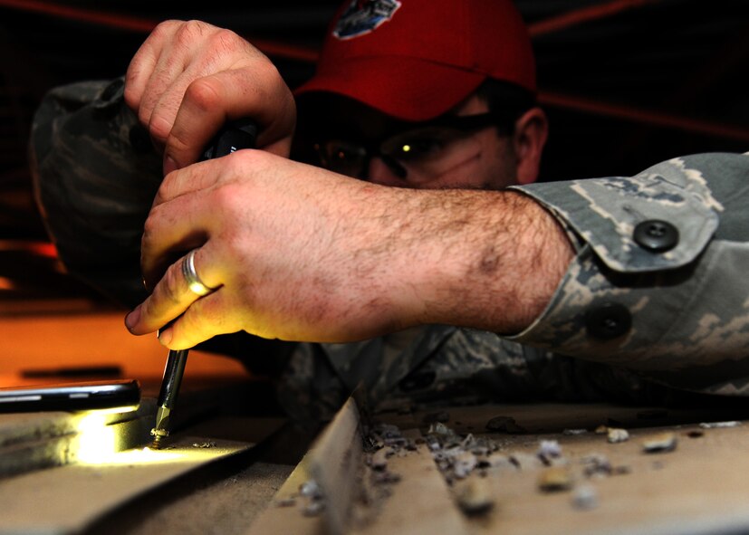 Senior Airman David Osbon, 307th RED HORSE Civil Engineer Squadron structural engineer, uses a flat-head screwdriver to remove a screw at the Airman Leadership School gym on Barksdale Air Force Base, La., Jan. 11, 2014. Osbon removed the screws to detach the supporting brackets on an old HVAC unit. After the brackets are removed the pieces of the HVAC unit can be sperated.  (U.S. Air Force photo/Senior Airman Joseph A. Pagán Jr.)