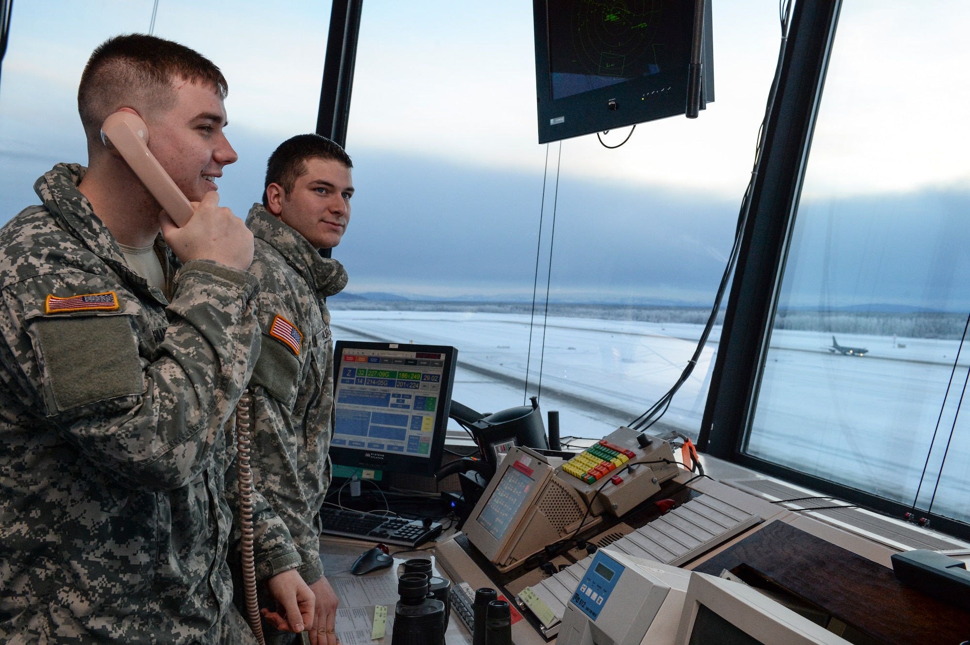 U.S. Army Spc. Christopher Smades speaks with a KC-135 Stratotanker pilot while Spc. Paul Murray watches the flight line for any hazards Jan. 14, 2014, Eielson Air Force Base, Alaska. Murray and Smades, Fox Company 1-51, Aviation Battalion air traffic control specialists, are training with Air Force air traffic controllers in preparation for an upcoming deployment. (U.S. Air Force photo by Airman 1st Class Peter Reft/Released)