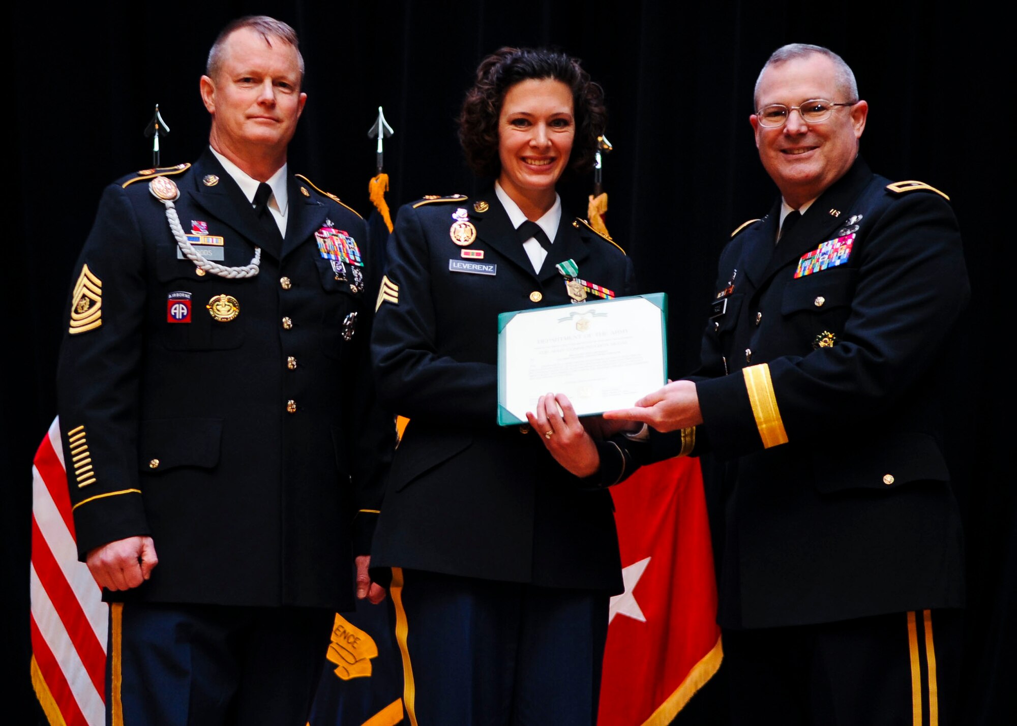 From left, U.S. Army Command Sgt. Maj. Dennis Woods, U.S. Army Training and Doctrine Command Initial Military Training command sergeant major, Sgt. Anna Leverenz, TRADOC Band member, and Maj. Gen. Ross Ridge, IMT deputy commanding general, exchange a certificate during the Soldier and Noncommissioned Officer of the year ceremony Jan. 13, 2014, at Fort Eustis, Va. Leverenz received the Soldier of the Year award from Ridge shortly after rising to the rank of Sergeant for her dedication to the TRADOC mission. (U.S. Air Force photo by Airman 1st Class Austin Harvill/Released)