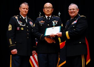 From left, U.S. Army Command Sgt. Maj. Dennis Woods, U.S. Army Training and Doctrine Command Initial Military Training command sergeant major, Sgt. Seongbok Park, 7th Sustainment Brigade, 11th Transportation Battalion cargo specialist, and Maj. Gen. Ross Ridge, IMT deputy commanding general, exchange a certificate during the Soldier and Noncommissioned Officer of the year award ceremony Jan. 13, 2014, at Fort Eustis, Va. Park received the NCO of the Year award for his outstanding work as a leader and Soldier. (U.S. Air Force photo by Airman 1st Class Austin Harvill/Released)