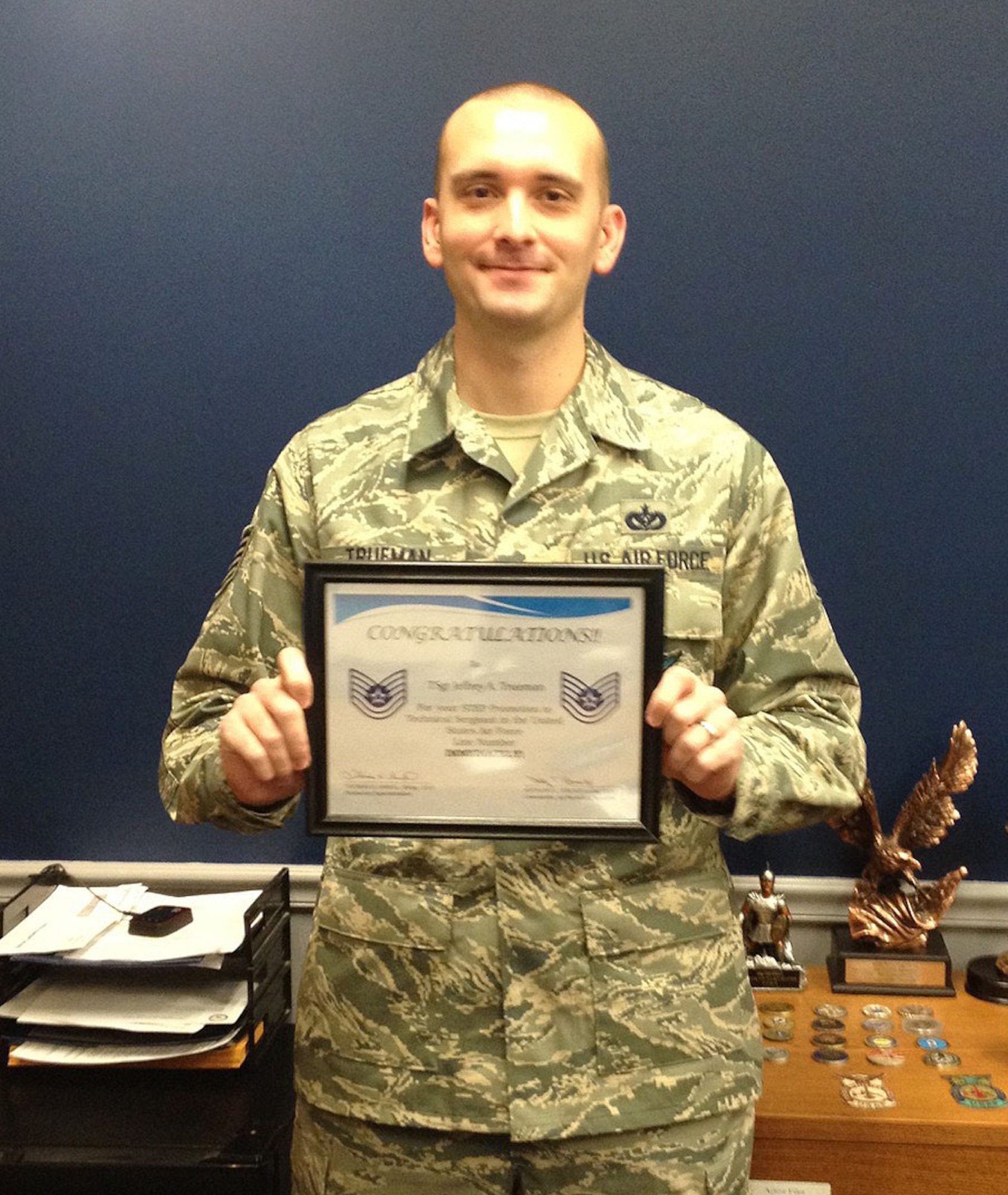 Tech. Sgt. Jeffrey Trueman holds up the Stripes for Exceptional Performers certificate he received at his surprise promotion ceremony Dec. 19. (U.S. Air Force photo)