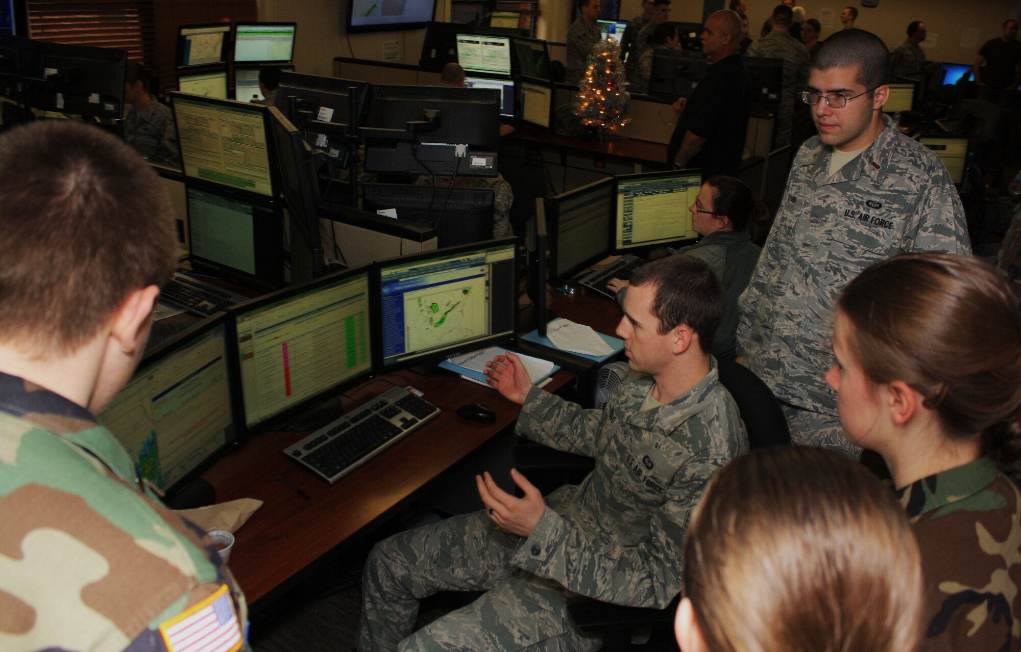 SrA Matthew Mannillo (seated), a shift supervisor with the 15th Operational Weather Squadron, describes the meteorological data he monitors from his work station to Scott Composite Squadron Cadet Senior Master Sgt. Zach Rawlings, Cadet Sara Jacobs, and Cadet Heather MacKeen (l to r) as 2nd. Lt. Ben Schink (15th OWS) looks on. (CAP photo by Capt. Greg Hoffeditz)