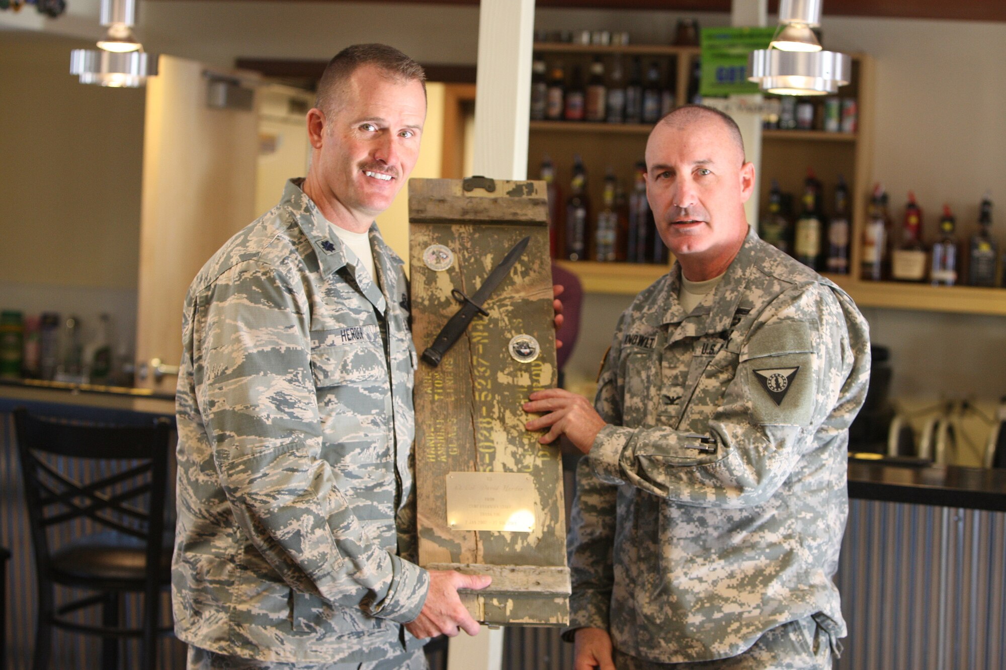 Wyo. Air National Guard Lt. Col. Dave Herder accepts a plaque signed by the fulltime staff at Camp Guernsey from Col. Richard Knowlton during a “Hail and Farewell” ceremony at the camp Nov. 26, 2013. Herder will leave the deputy commander position soon. (U.S. Army National Guard photo by Sgt. 1st Class Jimmy McGuire)
