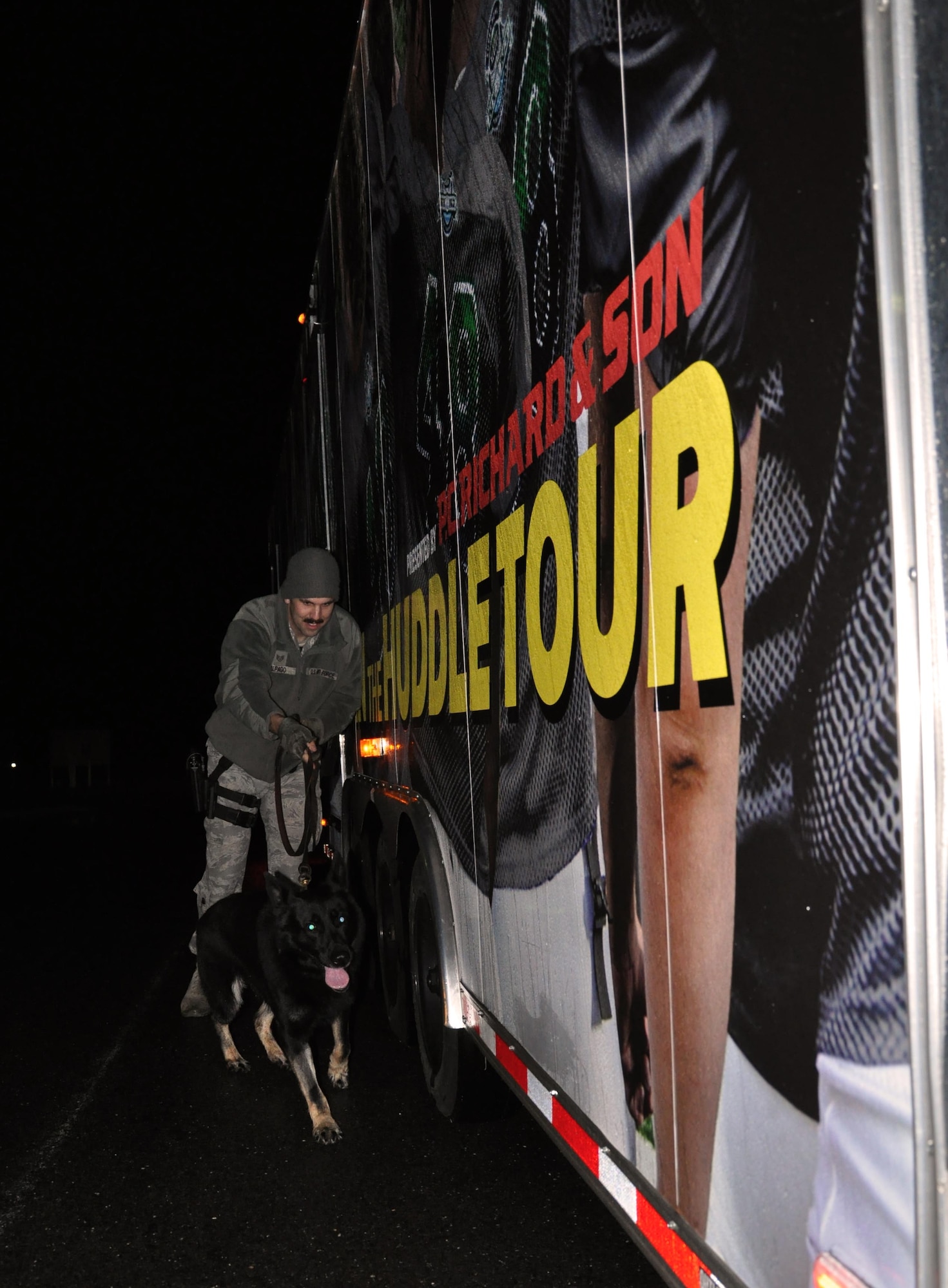 Staff Sgt. Corey Ray Alpagio, 87th Security Forces Squadron military working dog handler, directs his canine partner to inspect the Super Bowl exhibit truck, known as the Huddle Shuttle, as it enters the installation’s commercial truck gate Jan. 11, 2014, at Joint Base McGuire-Dix-Lakehurst, N.J. The truck was part of the ‘Join the Huddle Tour’ which was brought to JB MDL by the New York and New Jersey Super Bowl Host Committee and the NFL. (U.S. Air Force photo by 2nd Lt. Carrie Volpe/Released)