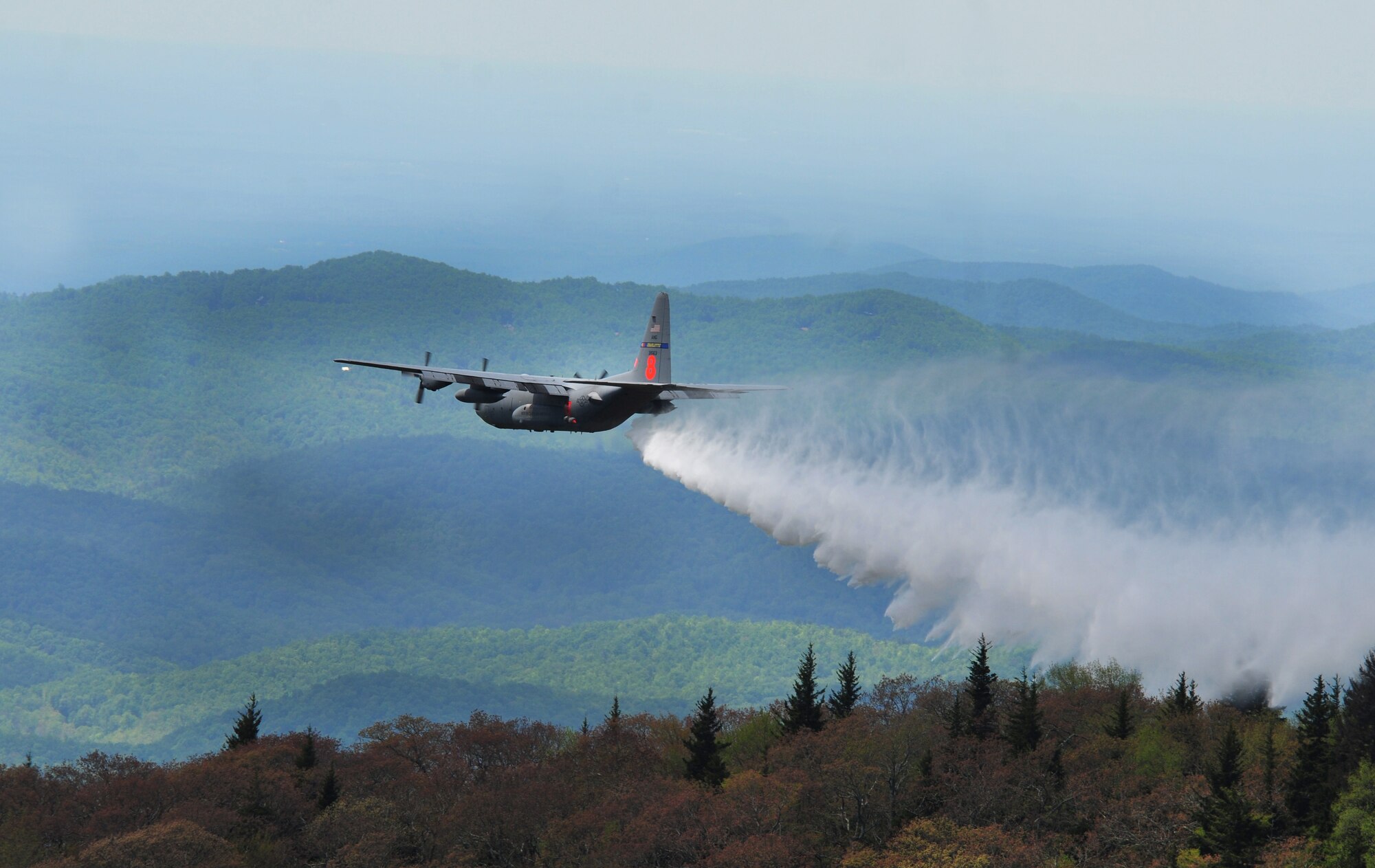 A North Carolina Air National Guard C-130 Hercules aircraft and her six man crew drop water (simulating fire retardant) during firefighting training operations over a remote portion of the Pisgah Ranger District, Pisgah National Forest.  The aircraft is carrying the self-contained Modular Airborne Fire Fighting System owned by the Forest Service.  As an interagency Defense Department and Forest Service program, MAFFS provides aerial firefighting resources when commercial and private air tankers are no longer able to meet the needs of the Forest Service. (Air National Guard photo by Master Sgt. Patricia F. Moran, 145th Airlift Wing Public Affairs/Released)
