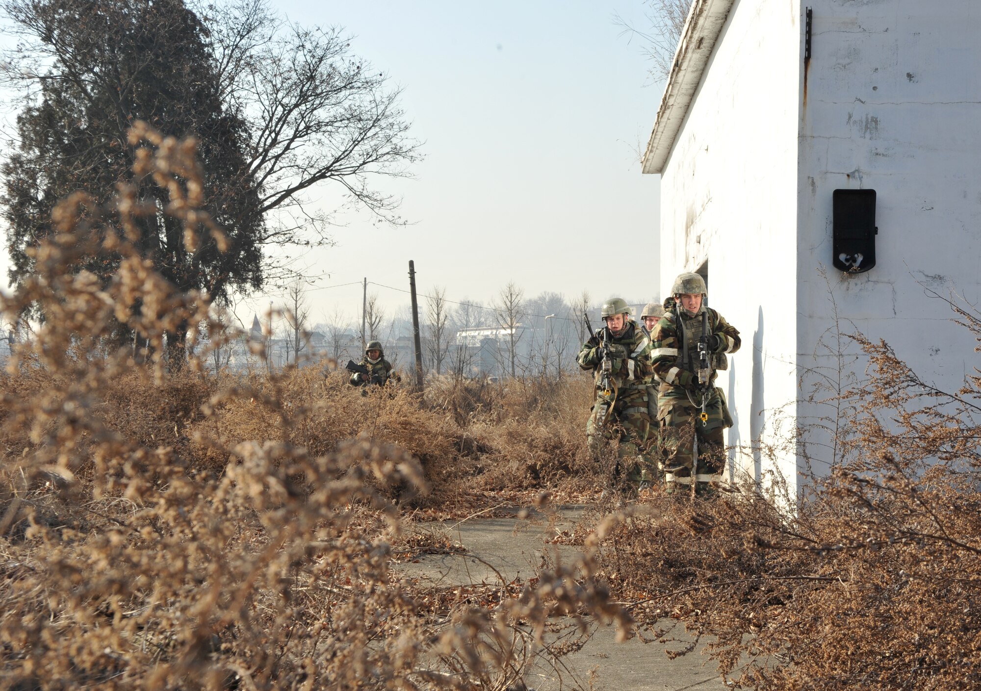 A group of Airmen from the 51st Security Forces Squadron emerge from a structure after checking for opposition forces role players during Operational Readiness Exercise Beverly Midnight 14-01 in a training area outside Osan Air Base, Republic of Korea, Jan. 14, 2014. The defenders moved through the training area in a formation designed to provide optimum safety and reconnaissance. (U.S. Air Force photo/Airman 1st Class Ashley J. Thum)