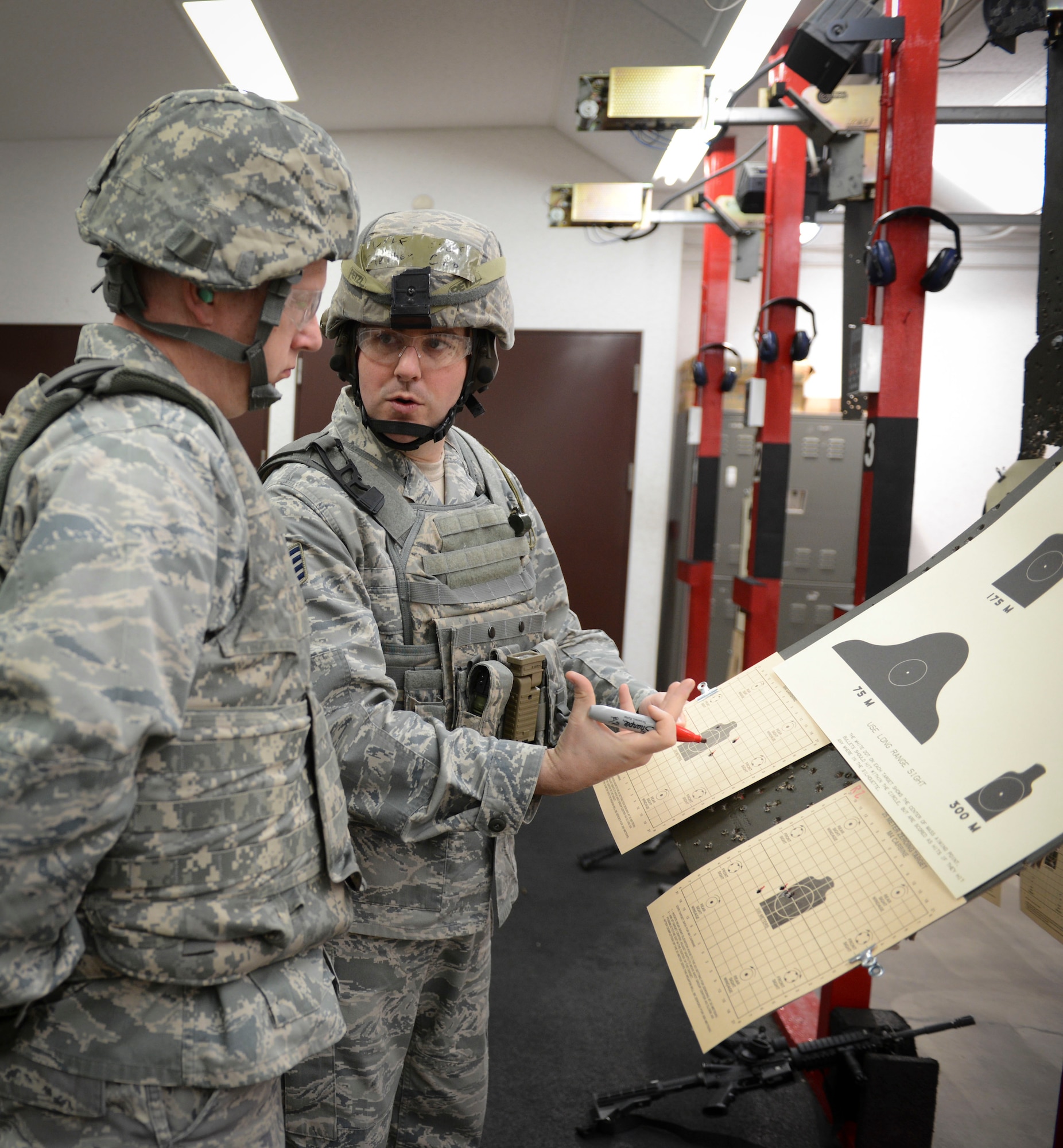 Staff Sgt. Stephen Ceo, 374th Security Forces Squadron combat arms instructor, grades an Airman's performance from the previous firing round at Yokota Air Base, Japan, Jan. 15, 2014.  In order to qualify for deployment in combat arms, each Airman must have at least a score of 44 out of 63 rounds to pass. (U.S. Air Force photo by Airman 1st Class Meagan Schutter/Released)