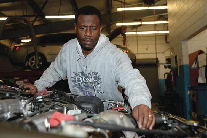 Lucien Sejour, equipment specialist, Marine Corps Systems Command, replaces the engine on a 1997 Toyota Camry he is repairing for his son.