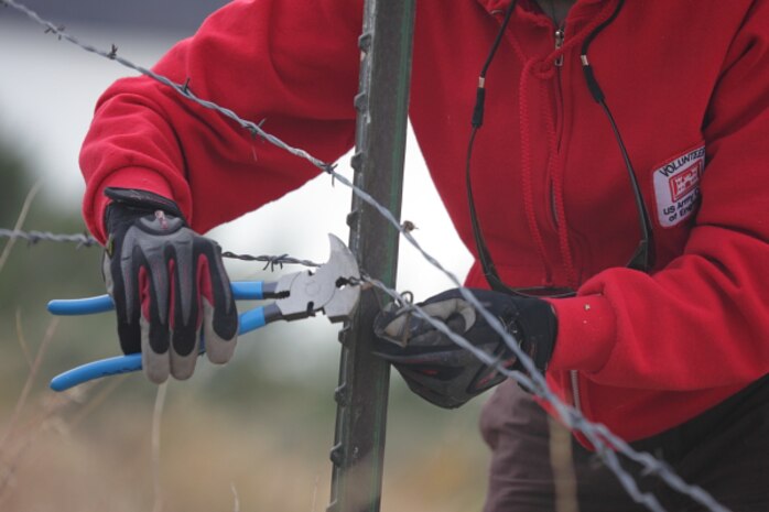 A volunteer assists with removing old wire fence to improve passage of wildlife across public lands.  Volunteers are invaluable force multipliers  on projects at Lucky Peak Lake.