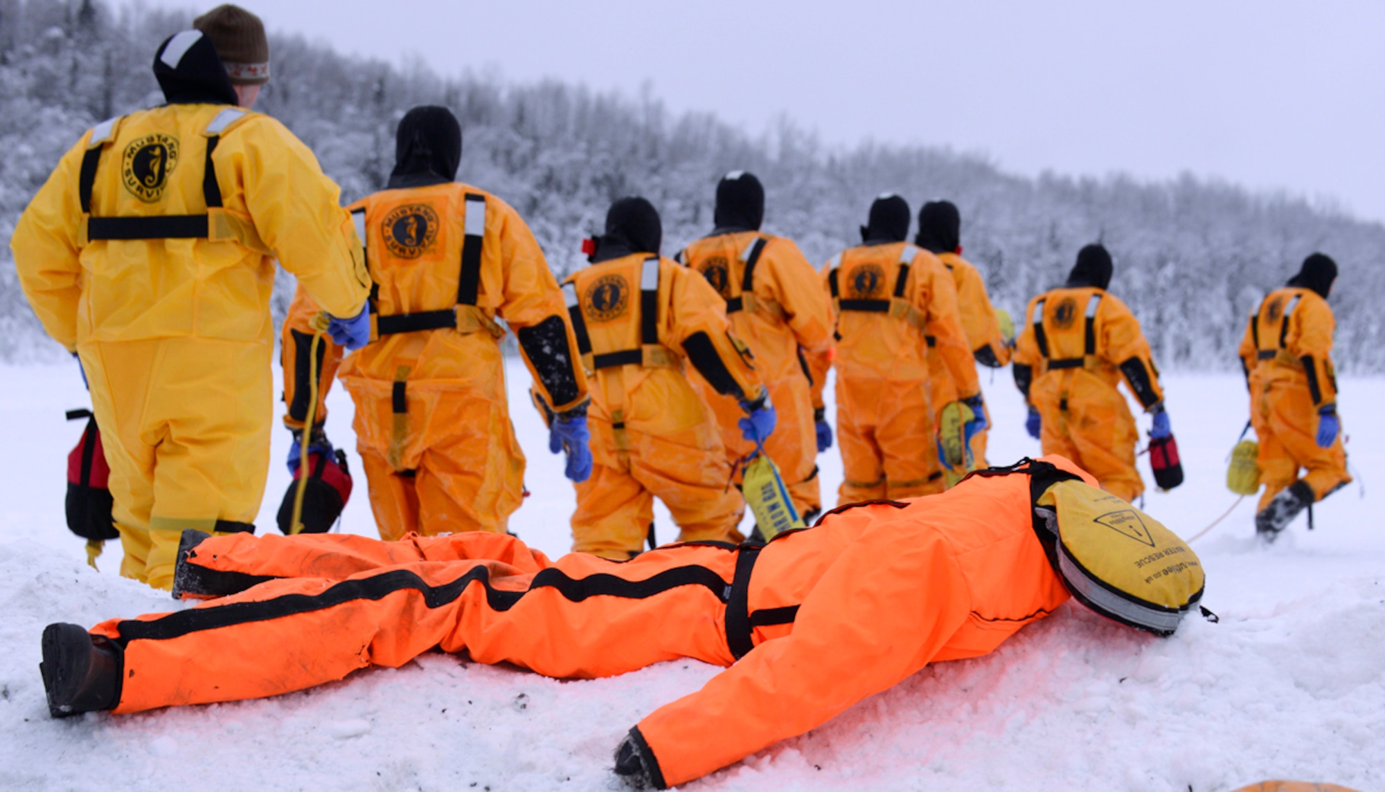 A water dummy rests on the snow embankment while firefighters of the 673d Civil Engineer Squadron head to Upper Sixmile Lake, Joint Base Elmendorf-Richardson, Alaska, Jan. 13, 2014, for their second phase of ice water rescue training. JBER firefighters are first responders providing protection to people, property, and the environment from fires and disaster, rescue and hazardous material responses. (U.S. Air Force photo/Staff Sgt. Sheila deVera)